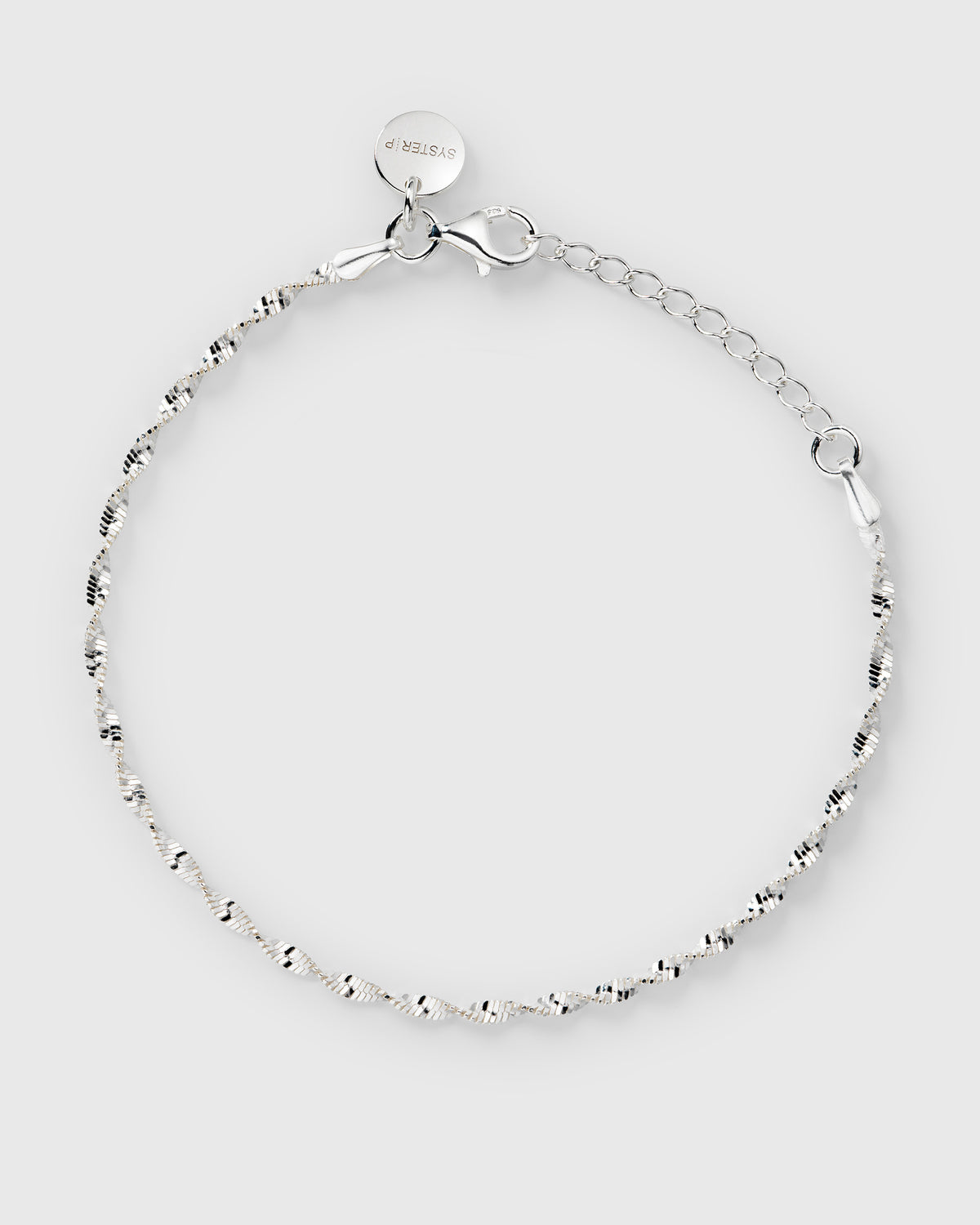 A product shot of the Advent Calendar Door 10 twisted herringbone bracelet in silver, laid out in a circle to display its delicate chain, clasp, and Syster P tag.