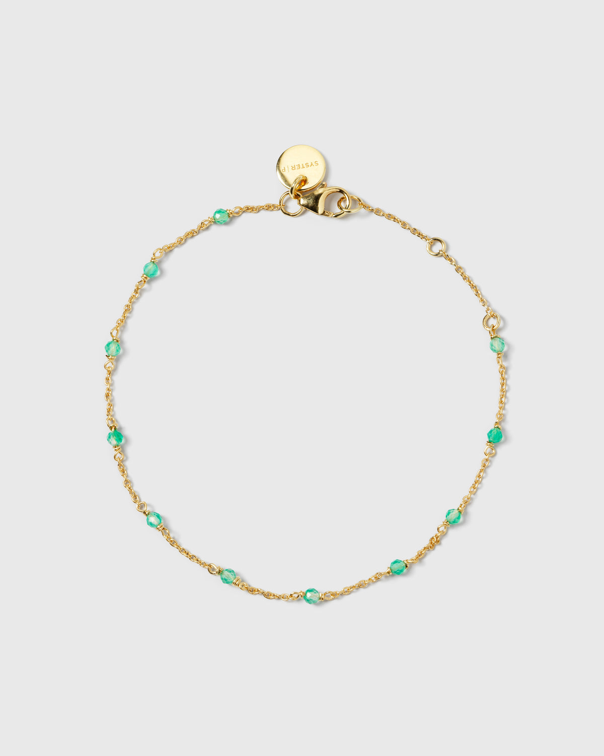 A product shot of the Santa Monica Bracelet in gold, laid out in a circle to display its delicate chain design adorned with small, faceted green onyx stones.