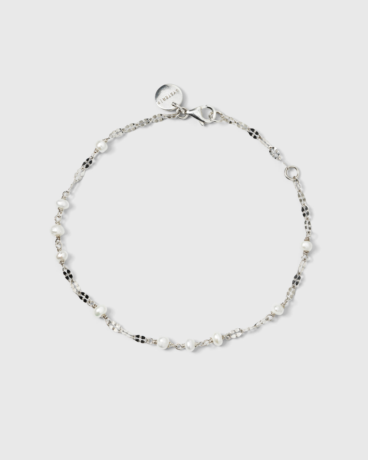 A product shot of the Aurelia Bracelet in silver, laid out in a circle to showcase its delicate chain with unique textured links interspersed with small freshwater pearls.