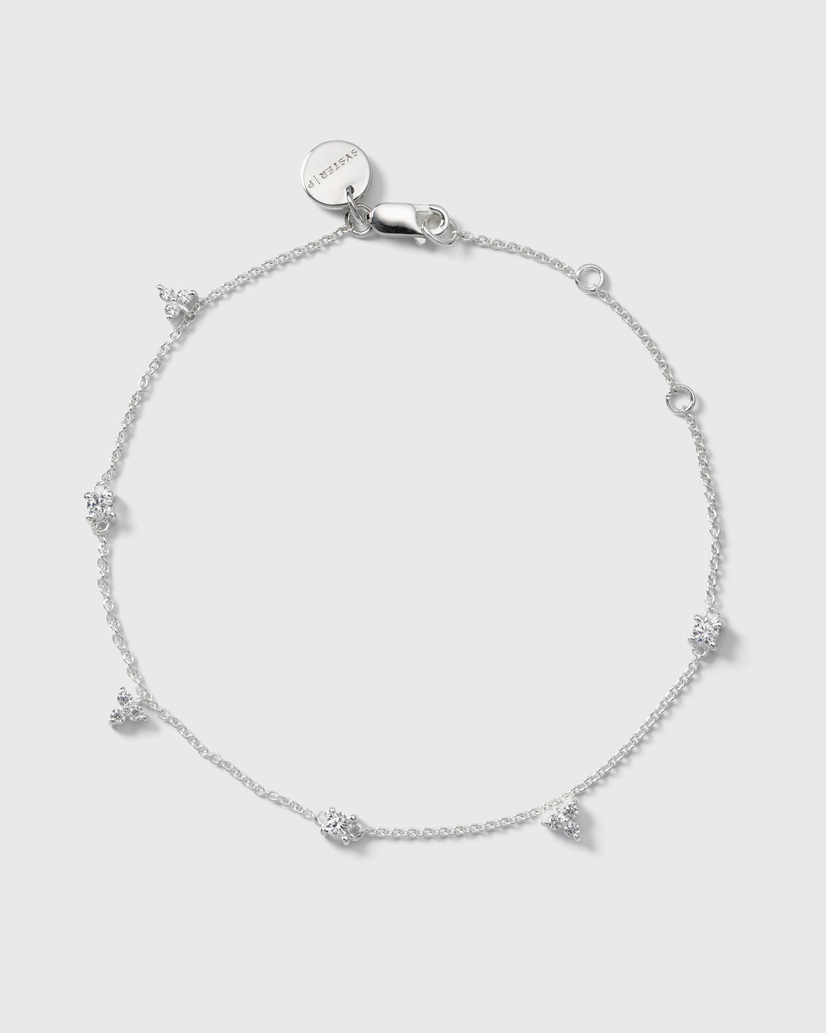 A product shot of the Celestia Bracelet in silver, laid out in a circle to display its delicate chain adorned with clusters of sparkling cubic zirconias.