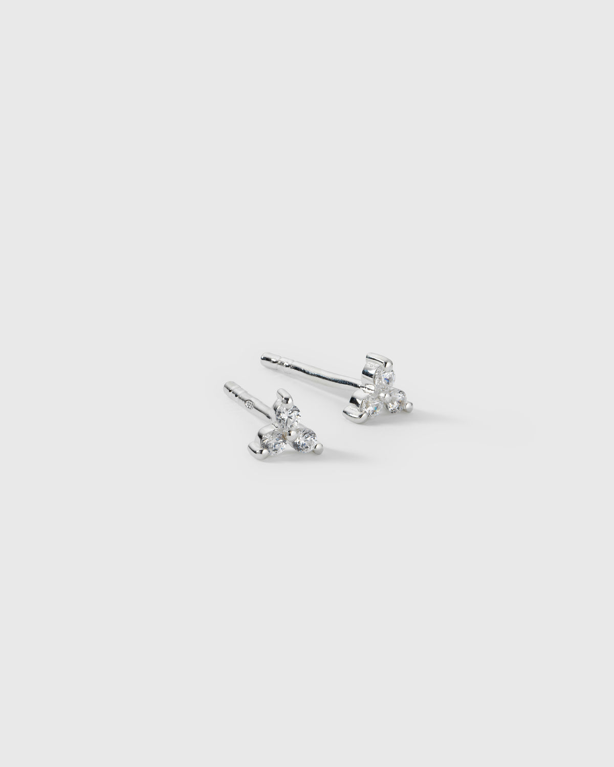 A product shot of the Celestia Triple Stone Studs in silver, each featuring three cubic zirconia stones that form a delicate flower-like pattern.