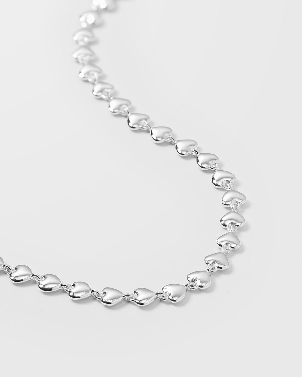 A close-up product shot of the Darling Necklace in silver, showcasing its unique chain which is made up of small, interconnected hearts.
