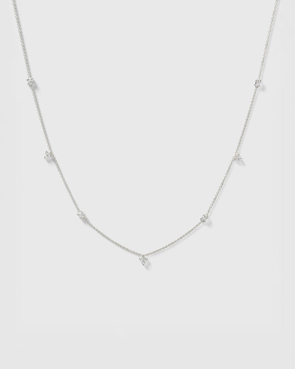 A product shot of the Celestia Necklace in silver, showcasing its fine chain adorned with several sparkling cubic zirconias in various shapes.