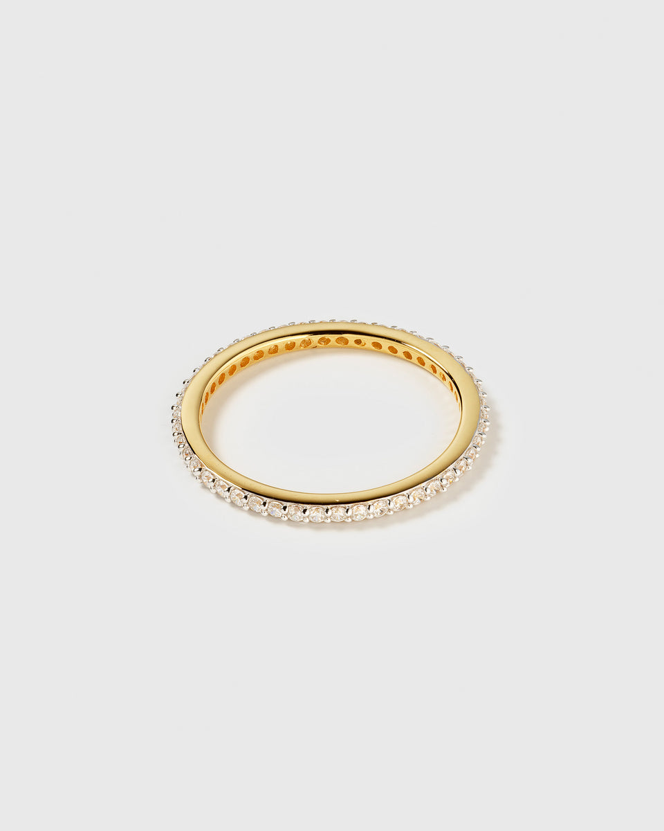 A product shot of the Tiny Sparkle Ring in gold, an eternity band fully set with small, sparkling white zirconias.