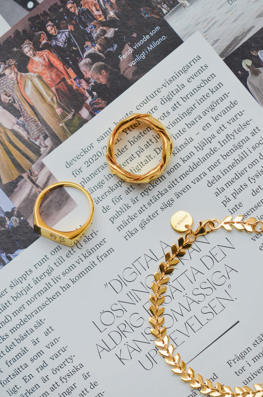 Layers Olivia Bracelet tillsammans med två ringar på ett tidningsuppslag.