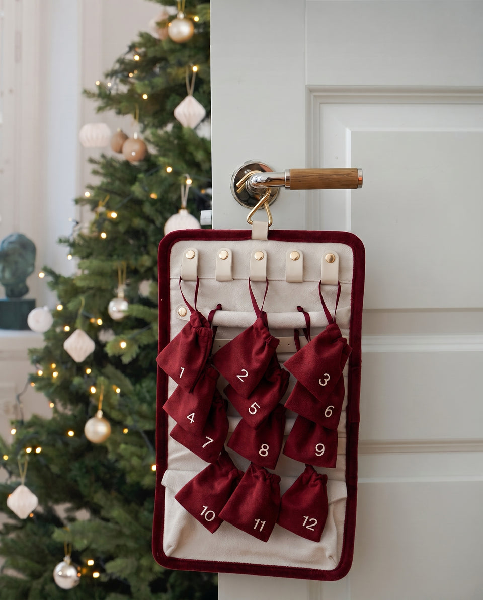 A lifestyle image of the Syster P Advent Calendar hanging on a door, showcasing the 12 doors