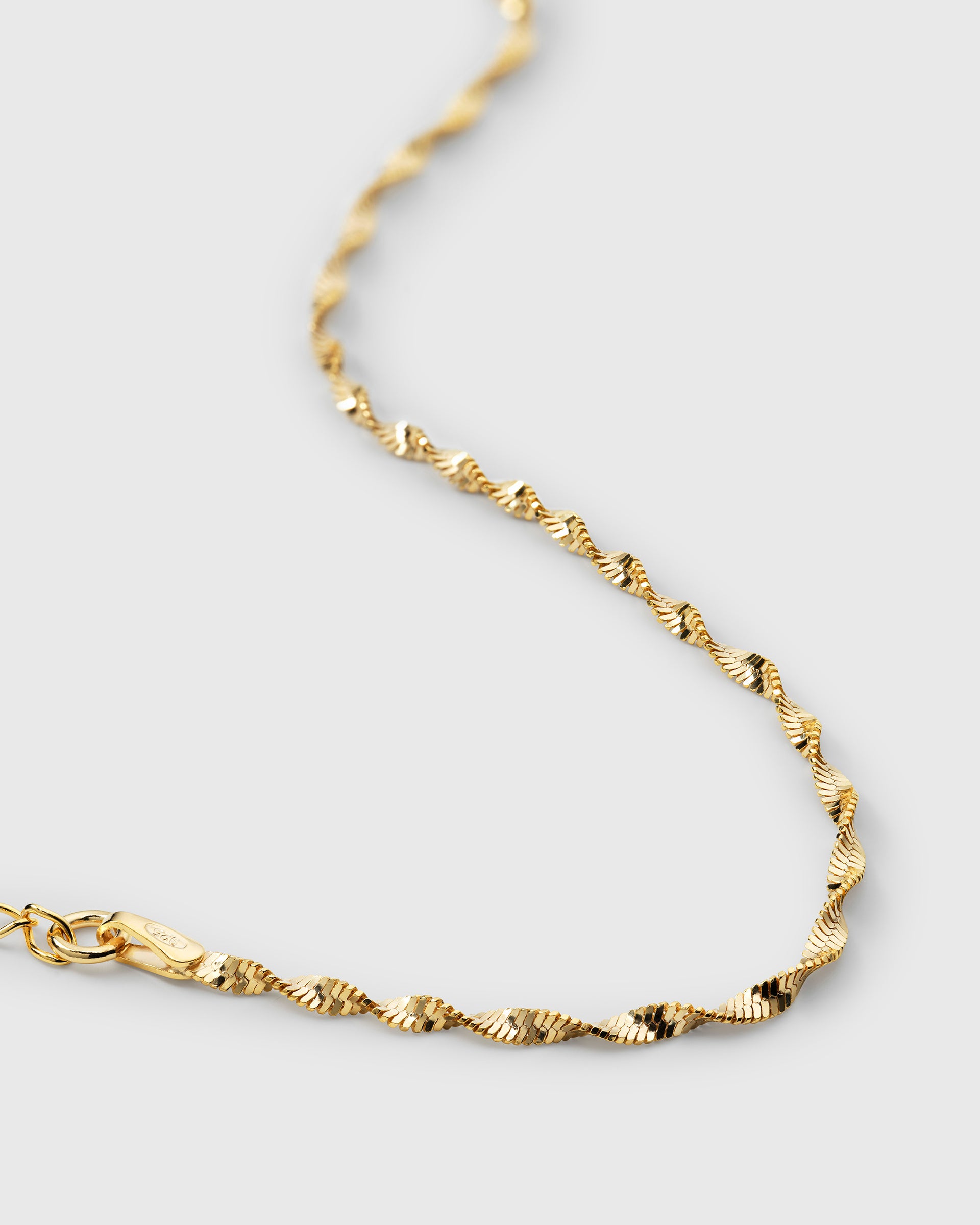 A close-up shot of the gold Herringbone Twisted Bracelet, showing its intricate, reflective twisted design.