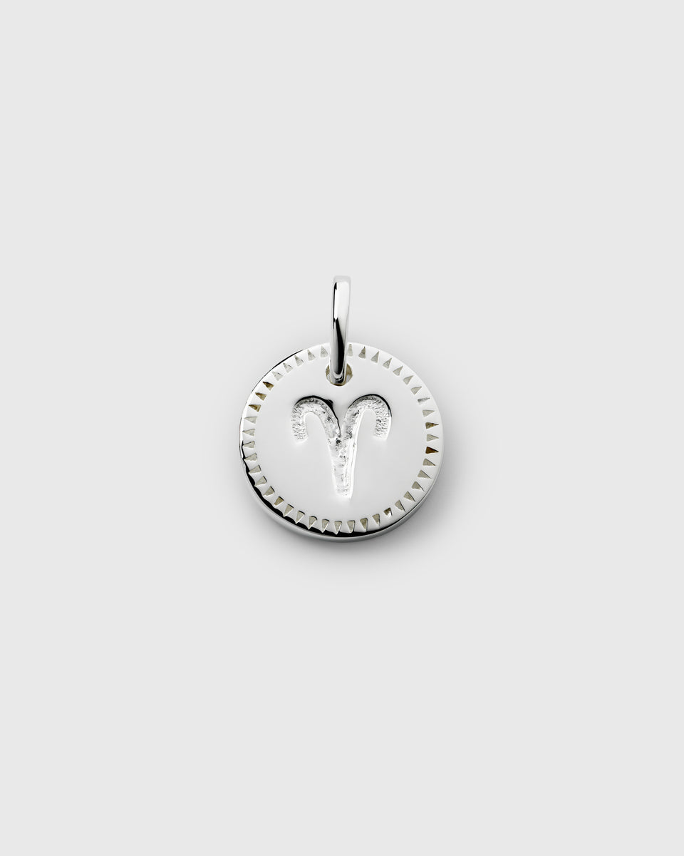 A product shot of the Beloved Zodie Pendant in silver, showcasing the Aries variant with its engraved zodiac symbol and a decorative triangular border.