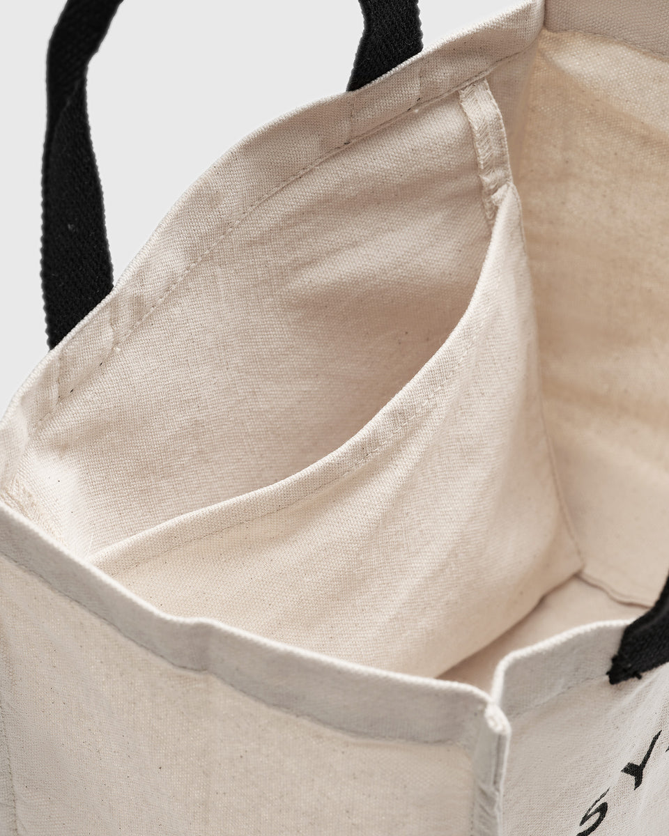 A close-up shot of the Syster P Lunch Tote, showing the inside of the beige cotton bag and its small inner pocket.