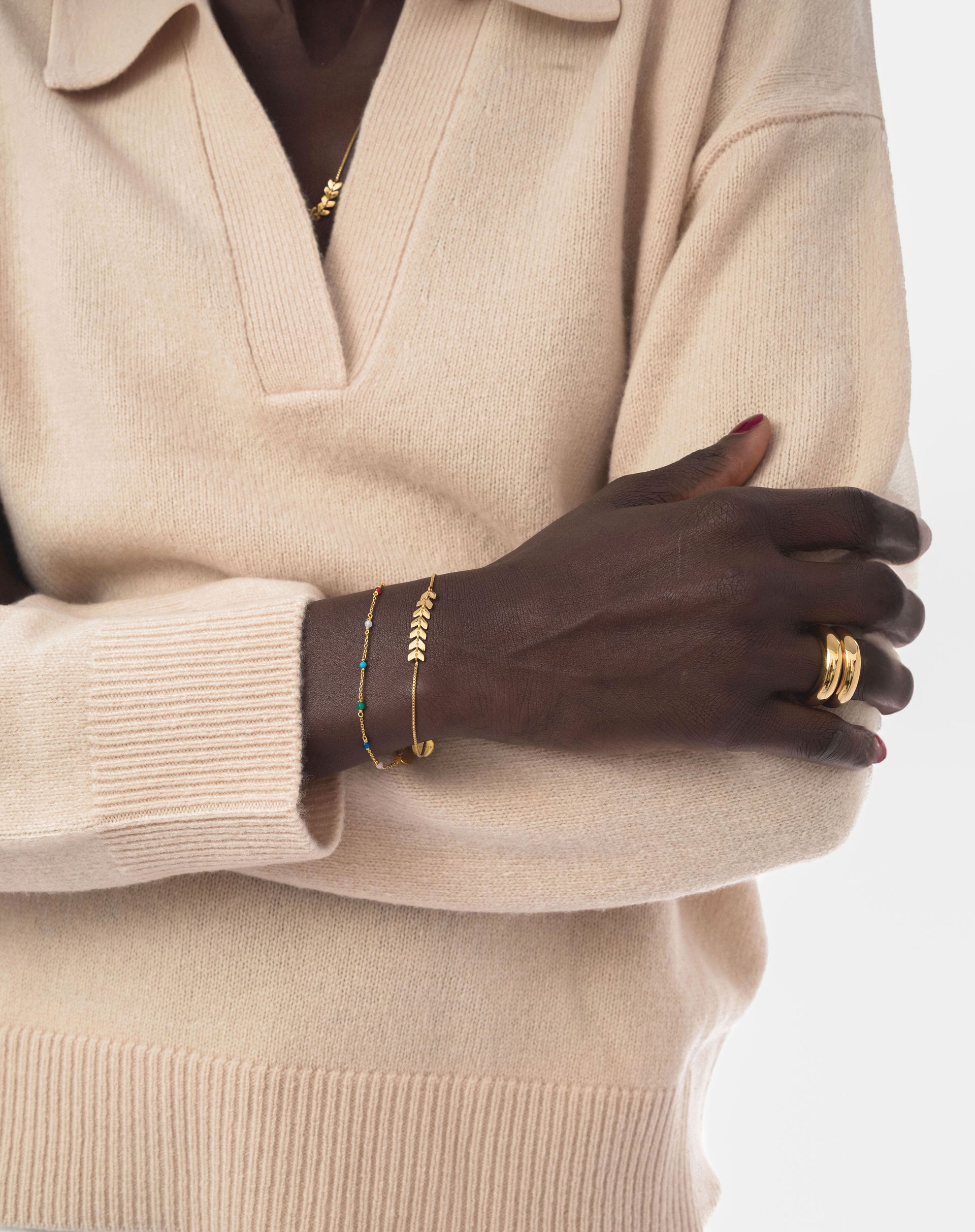 A model wears the Layers Simone Bracelet in gold, styled with a thin gold beaded bracelet, two chunky gold rings, and a matching Layers Simone necklace.