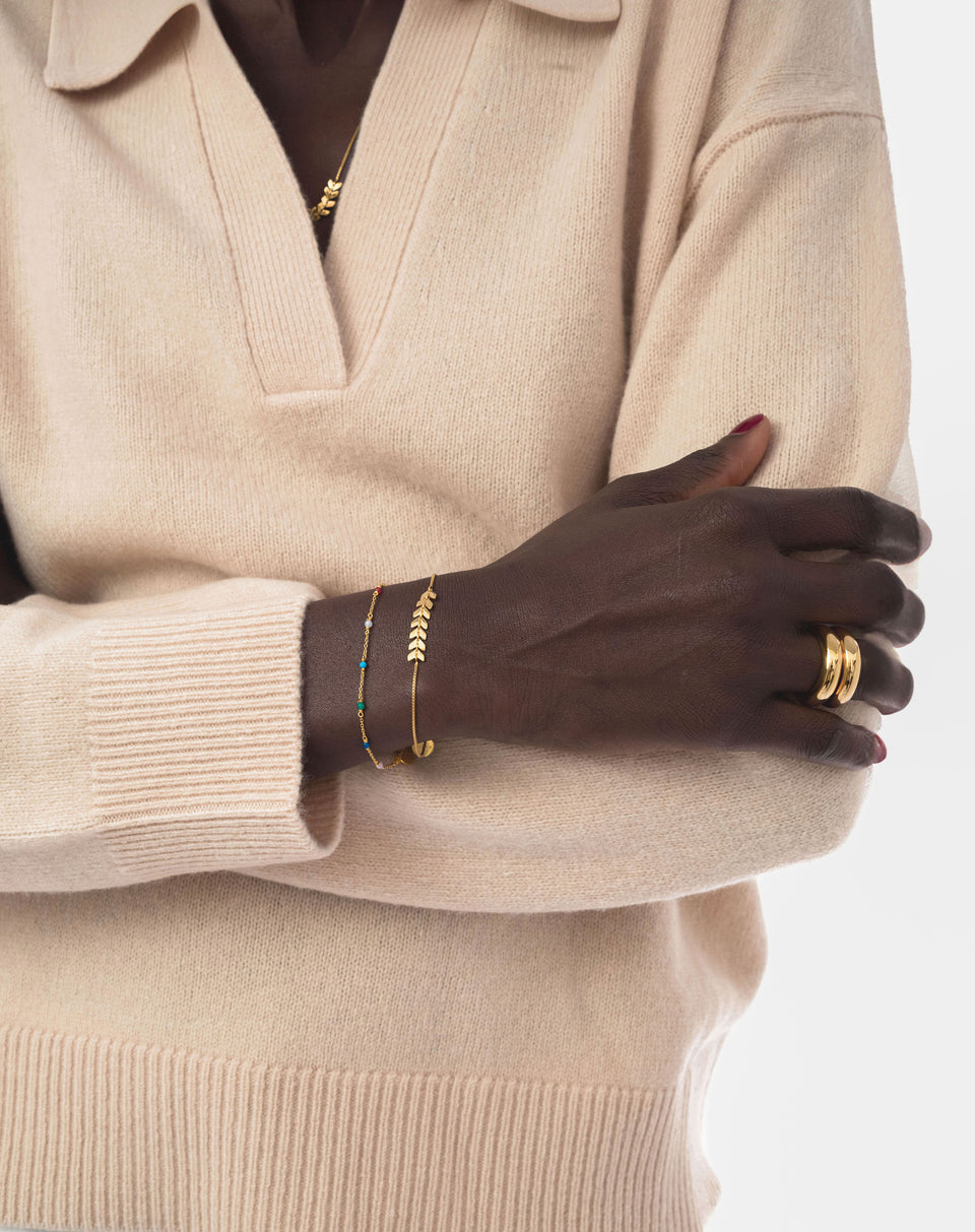 A model wears the Layers Simone Bracelet in gold, styled with a thin gold beaded bracelet, two chunky gold rings, and a matching Layers Simone necklace.