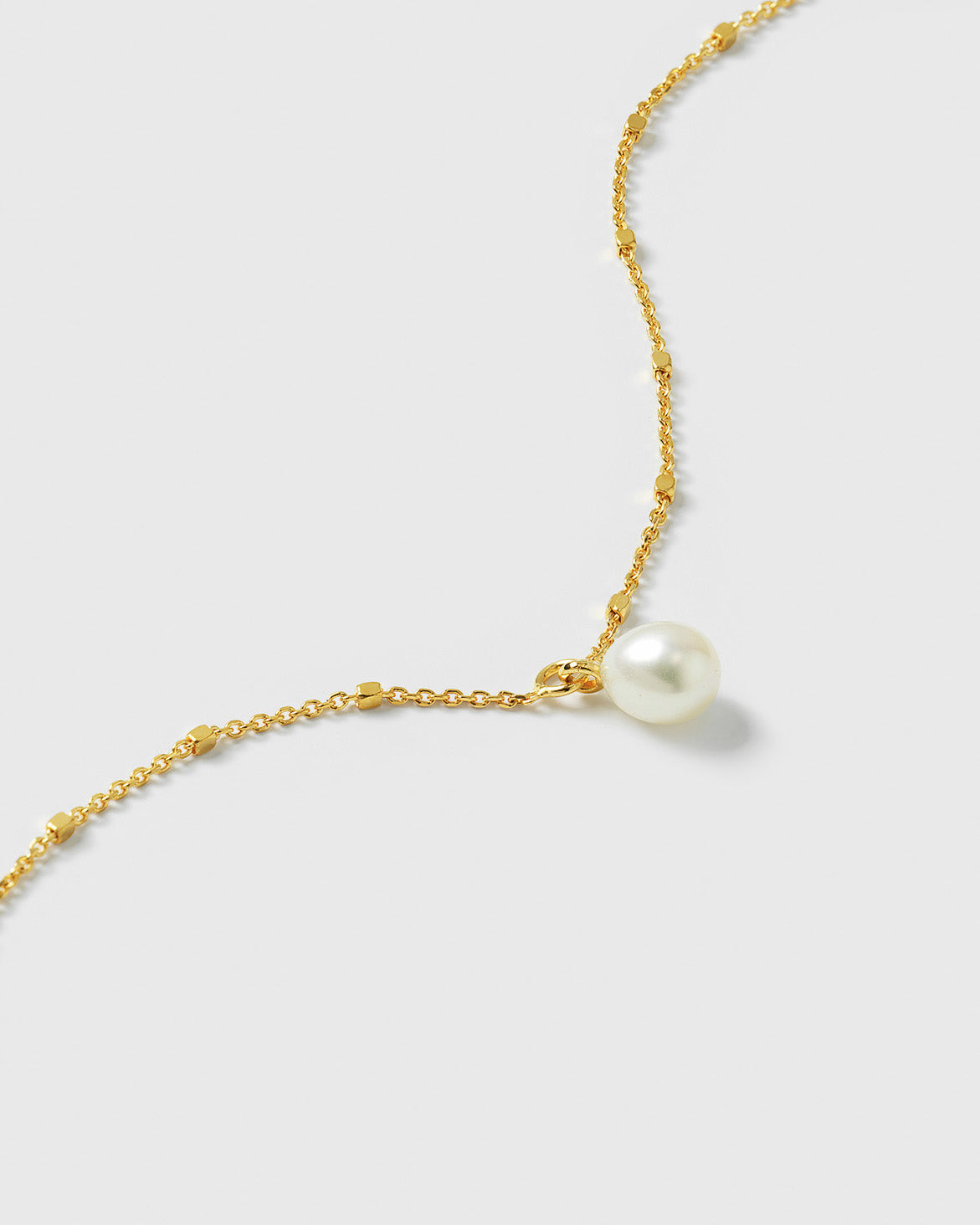 A close-up shot of the Treasure Single Pearl Bracelet in gold, showcasing the unique chain design with tiny shining dots and the single, teardrop-shaped freshwater pearl.
