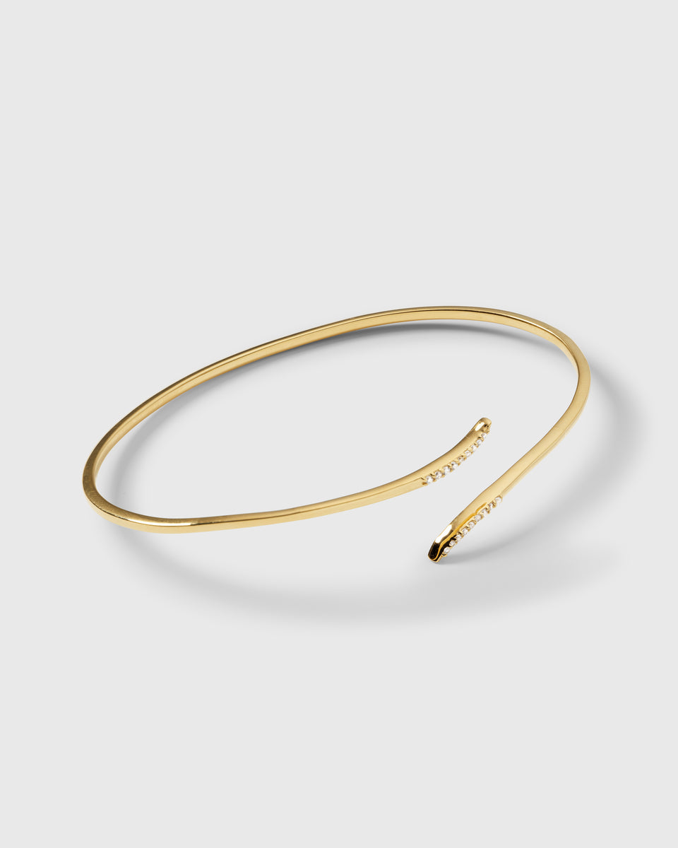 A product shot of the Sparkle Wrap Bangle in gold, an open wrap-style bangle with curved ends adorned with sparkling cubic zirconia stones.