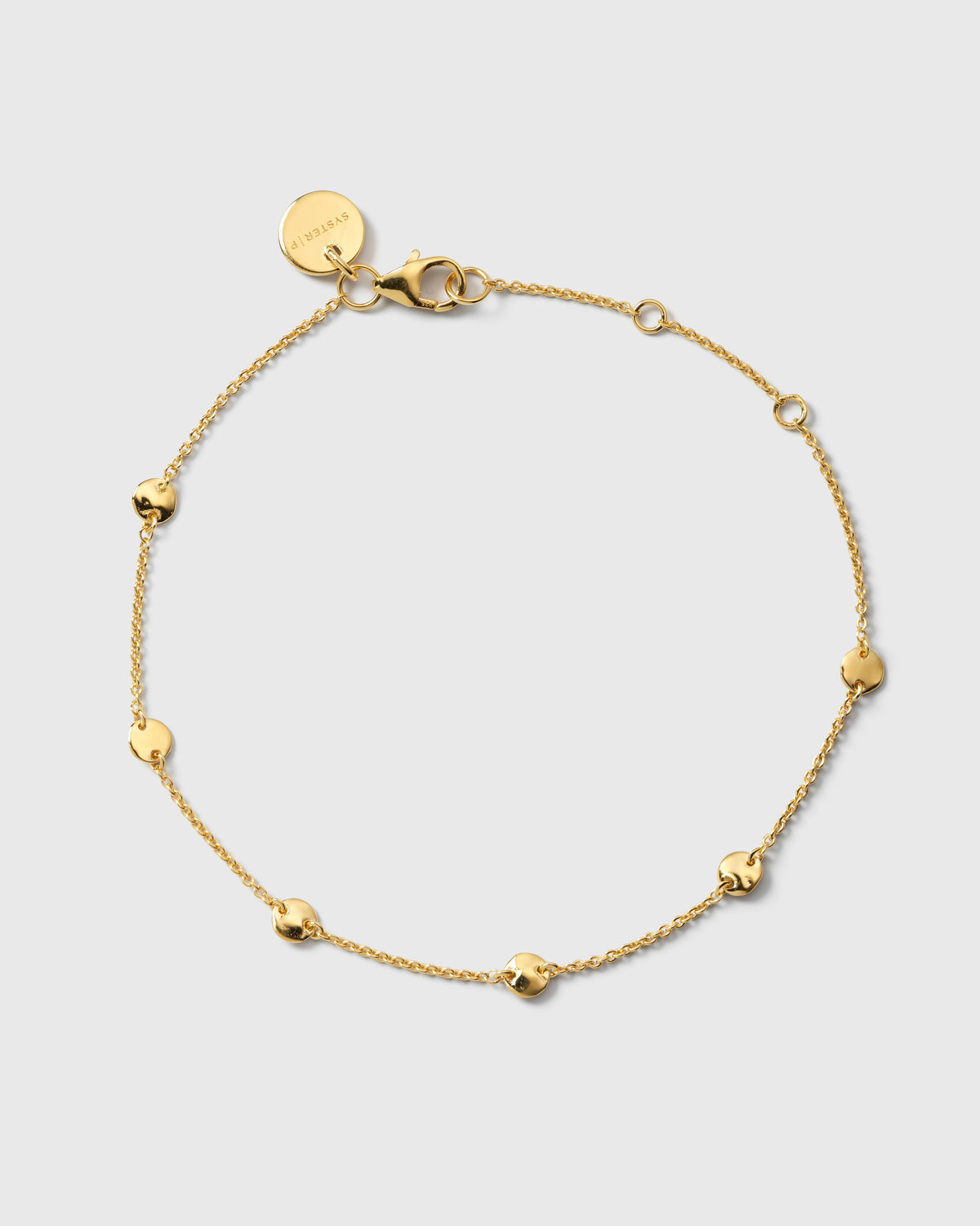 A product shot of the Solea Bracelet in gold, laid out in a circle to show its design of a delicate chain adorned with small, round hammered circles.