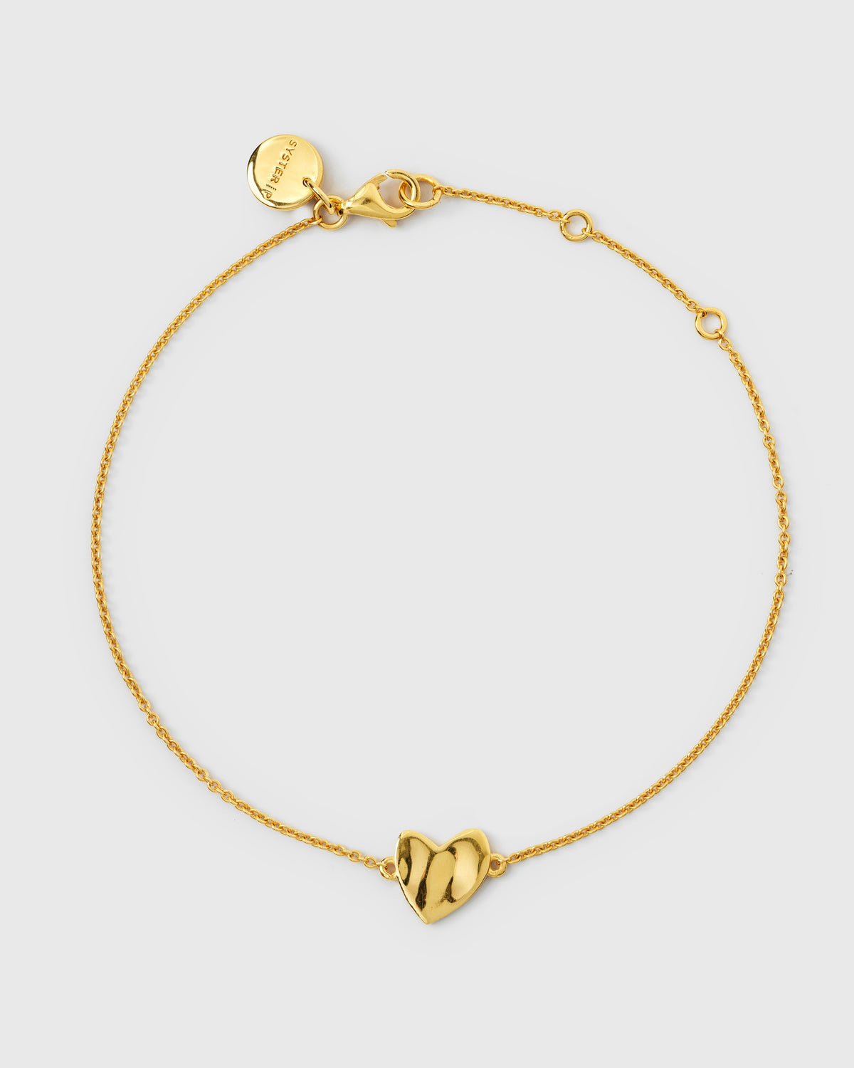 Gold bracelet with a delicate chain and a central hammered heart charm.