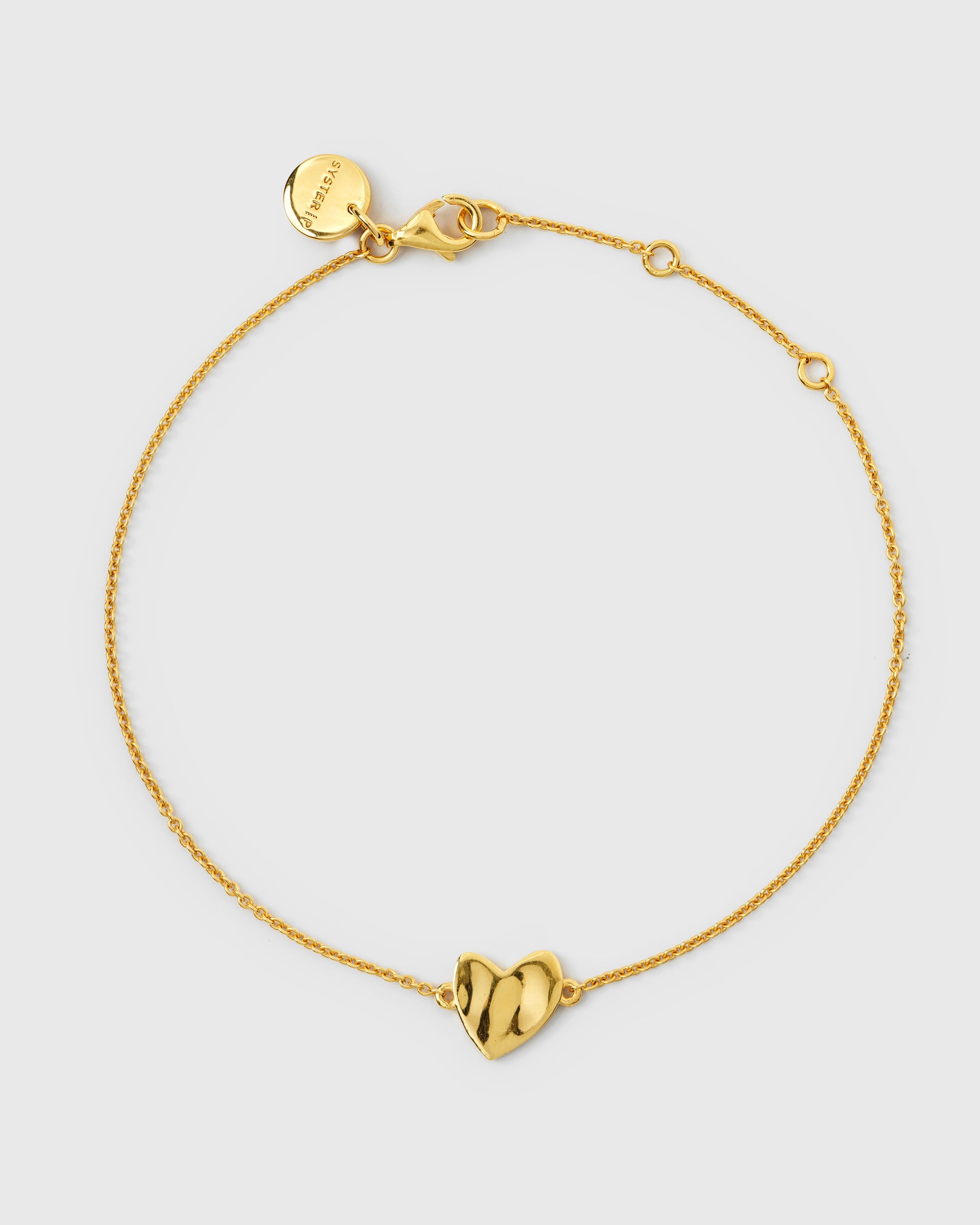 Gold bracelet with a delicate chain and a central hammered heart charm.