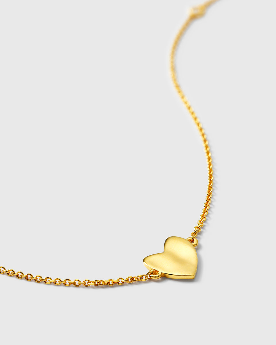 Gold bracelet with a hammered heart charm on a delicate oval chain.