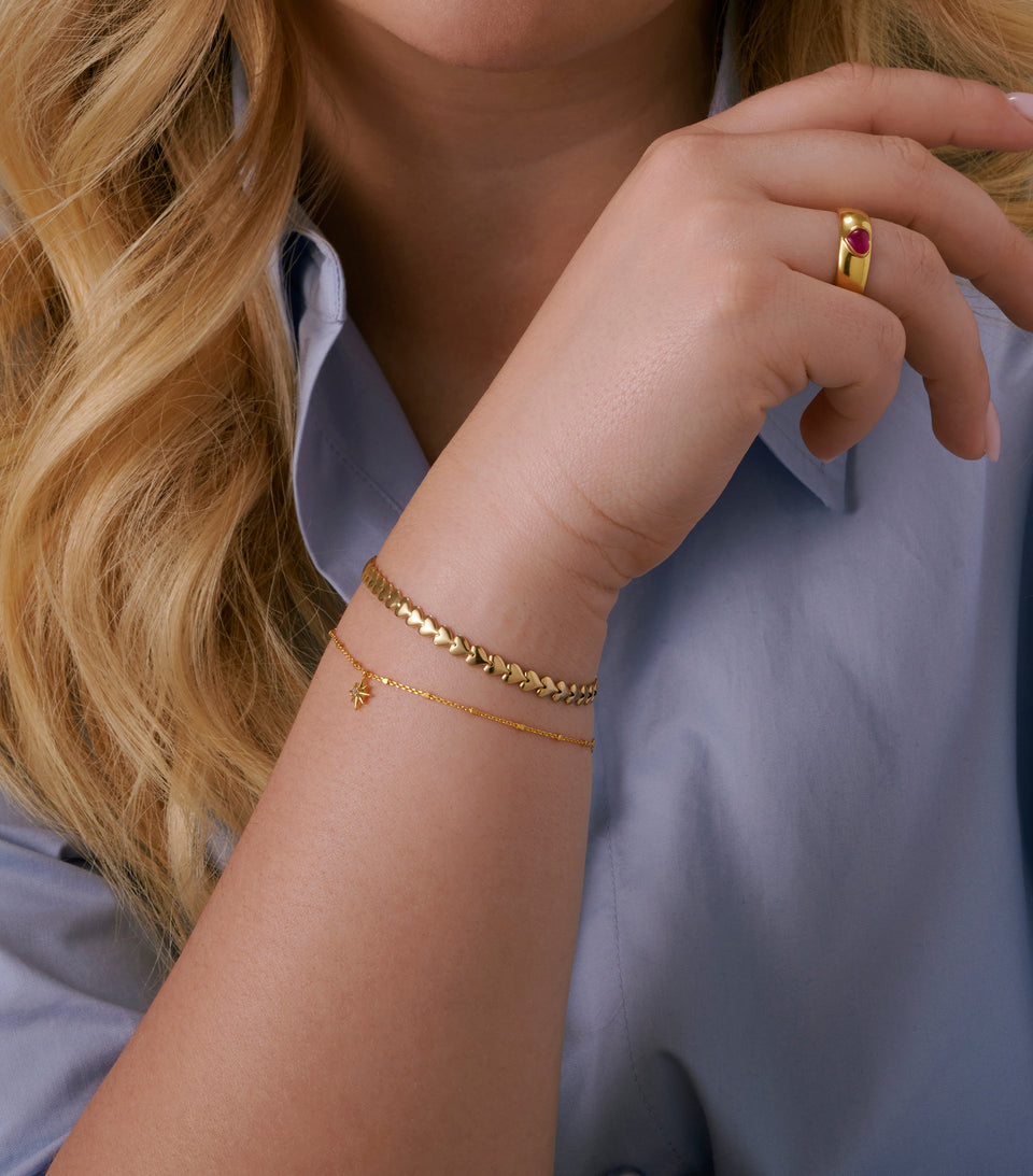 A close up shot of a model wearing the Darling Bracelet Silver, featuring a chain of connected hearts.