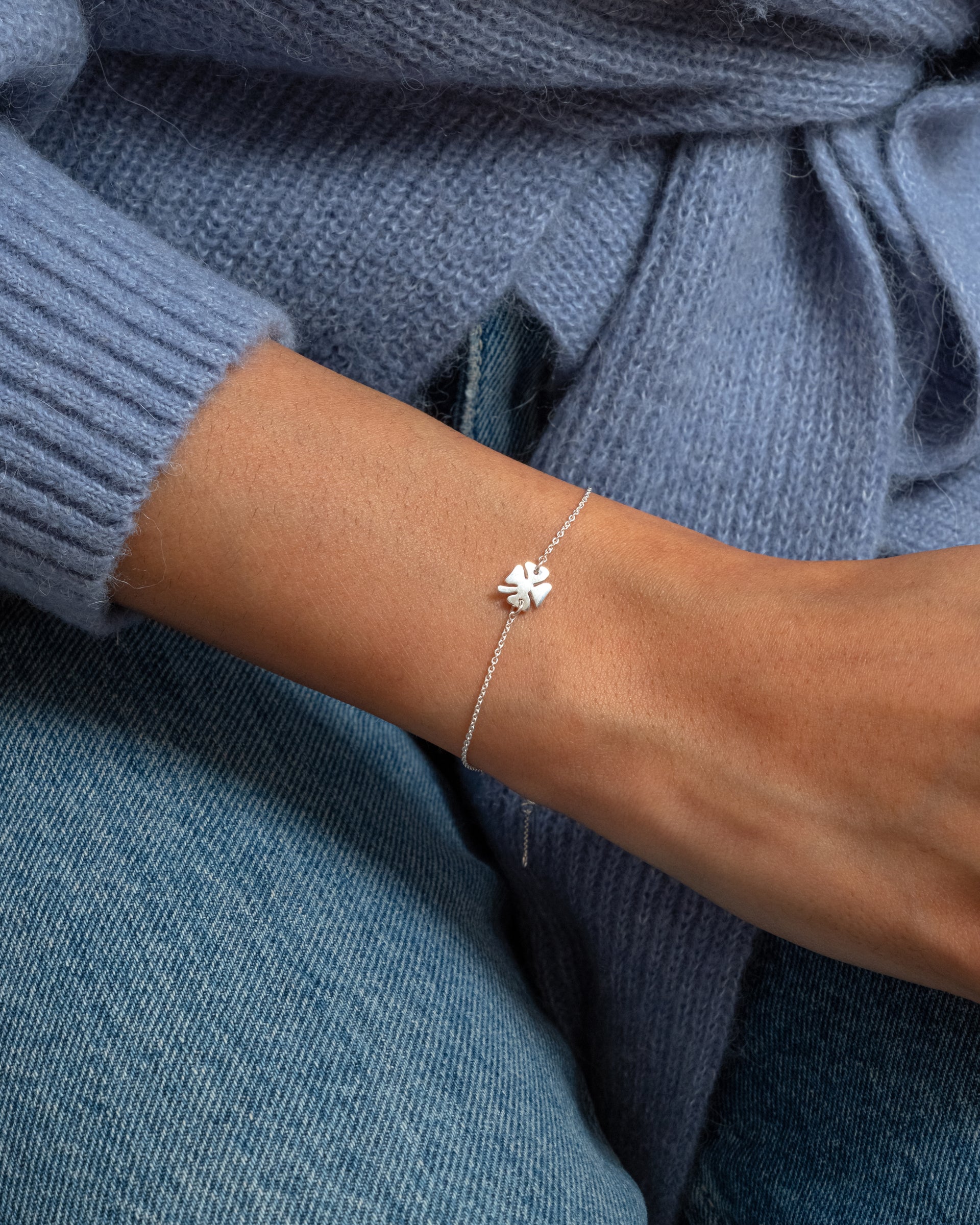 A close-up of a model wearing the Bring Me Luck Bracelet in silver, highlighting its delicate chain and four-leaf clover pendant.