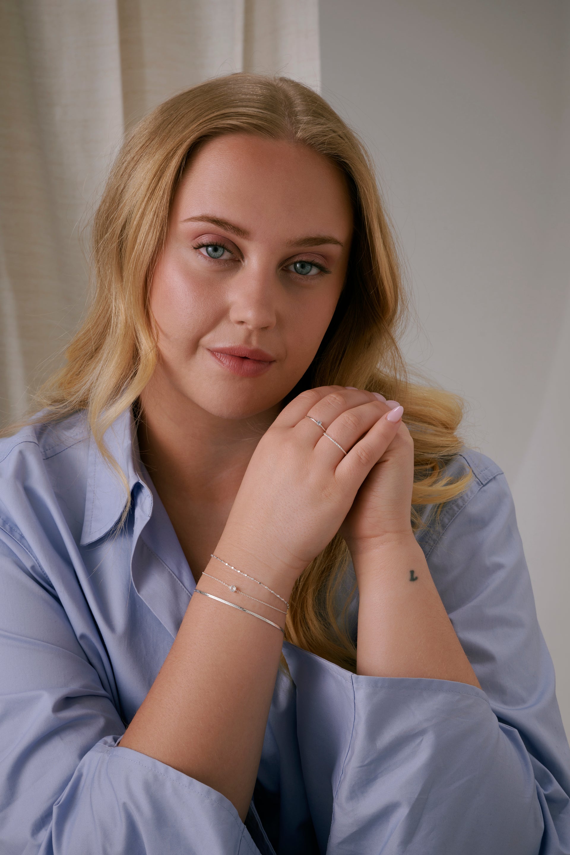 A model wearing the Silver Herringbone Bracelet, styled with two other silver bracelets 