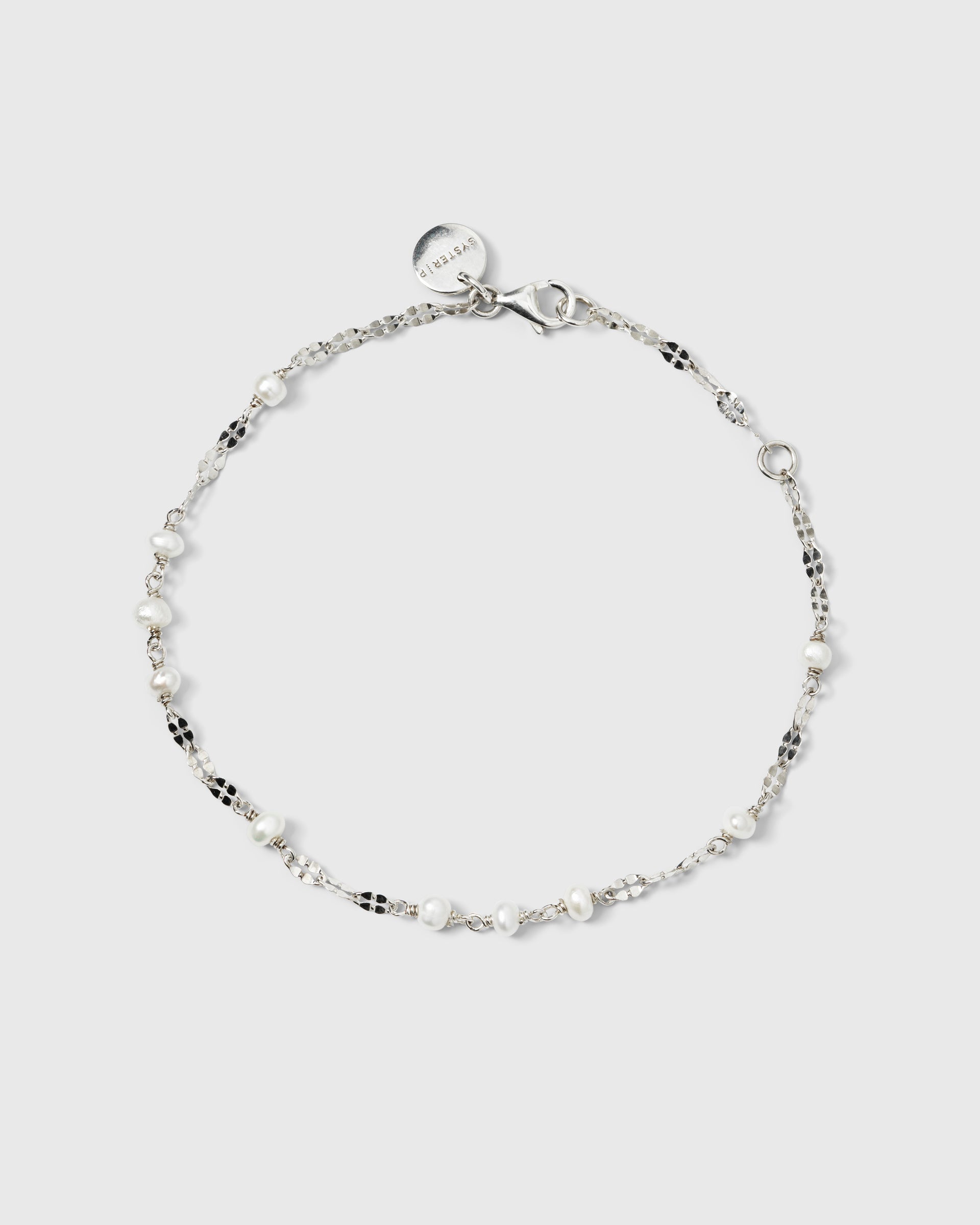A product shot of the Aurelia Bracelet in silver, laid out in a circle to showcase its delicate chain with unique textured links interspersed with small freshwater pearls.