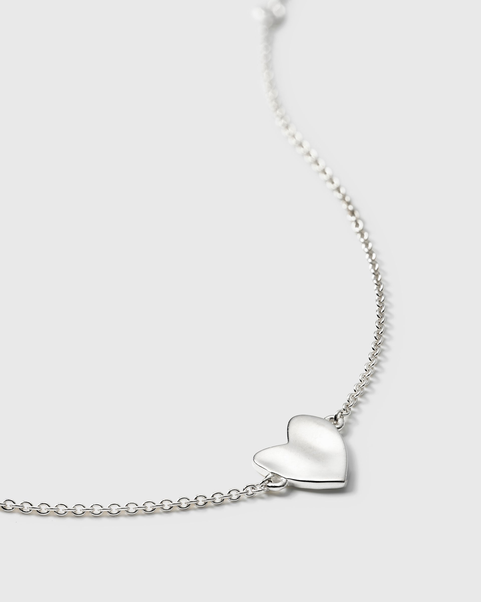 A bracelet in silver, showcasing the unique hammered heart charm on its delicate chain.