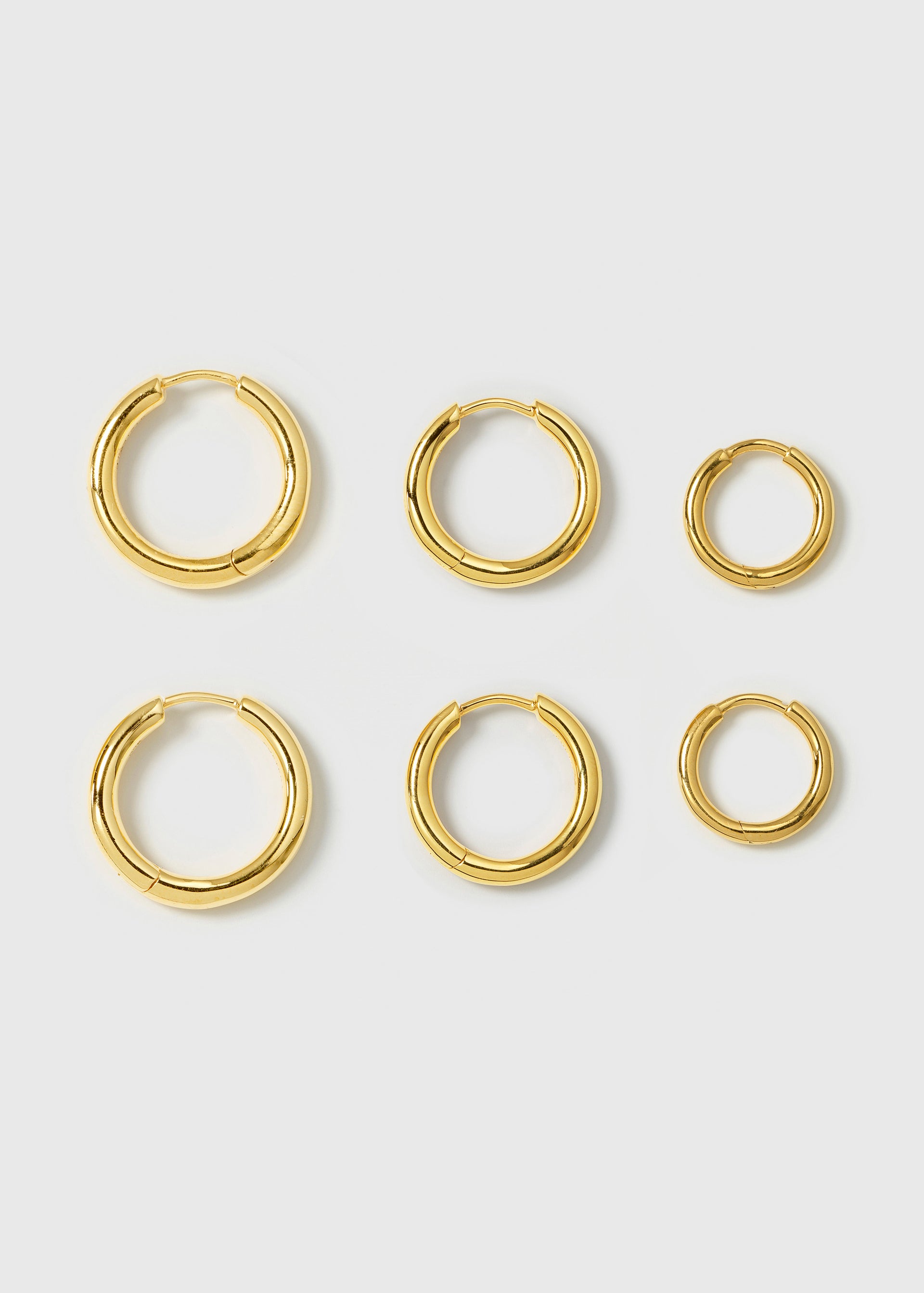 A product shot of the Beloved Fat Hoops Set in gold, laid out to showcase the three pairs of thick hoop earrings in large, medium, and small sizes.