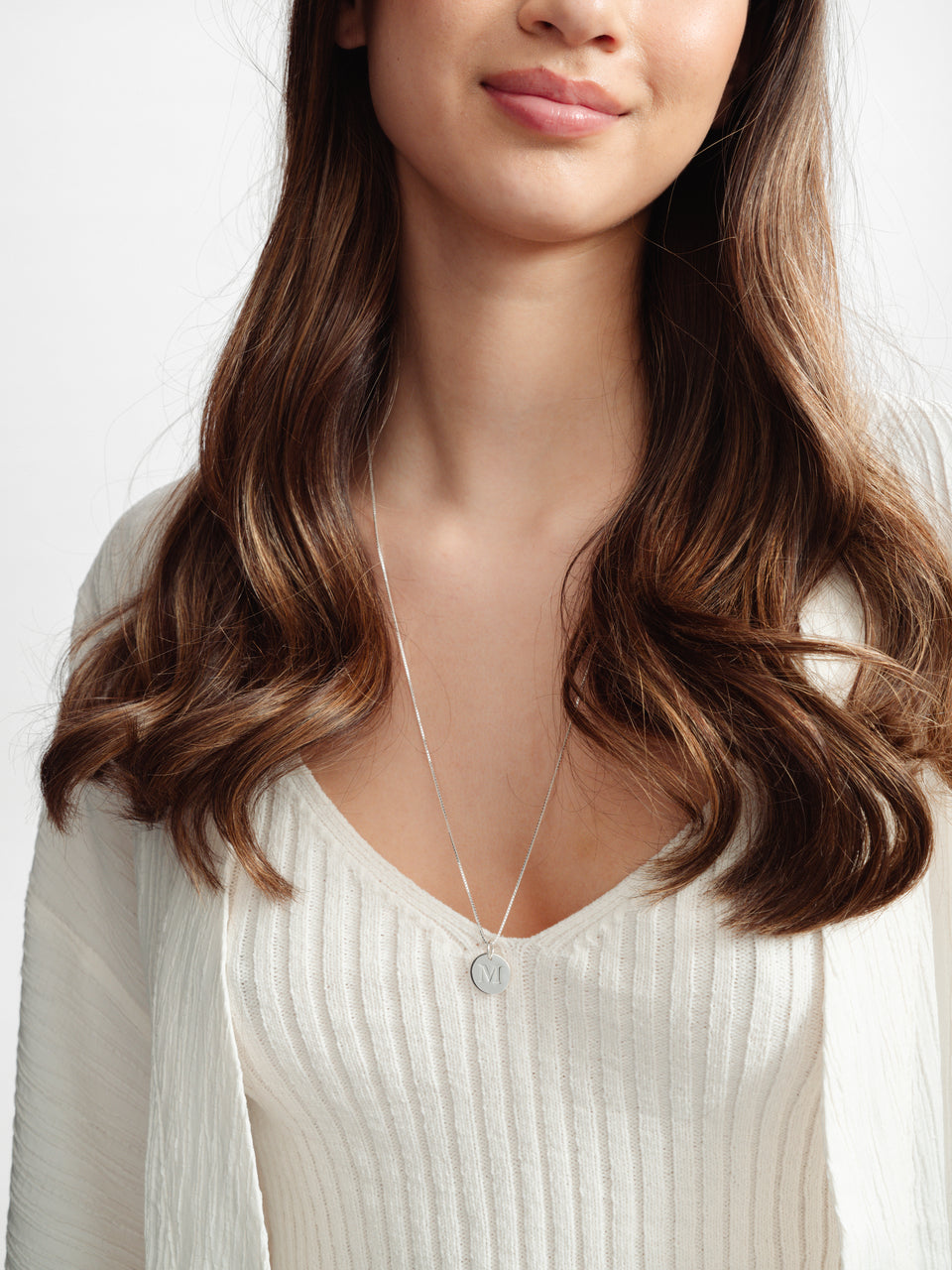 A close-up shot of a model wearing the Beloved Long Box Chain Silver necklace, paired with a round Beloved Big Letter 'M' pendant.