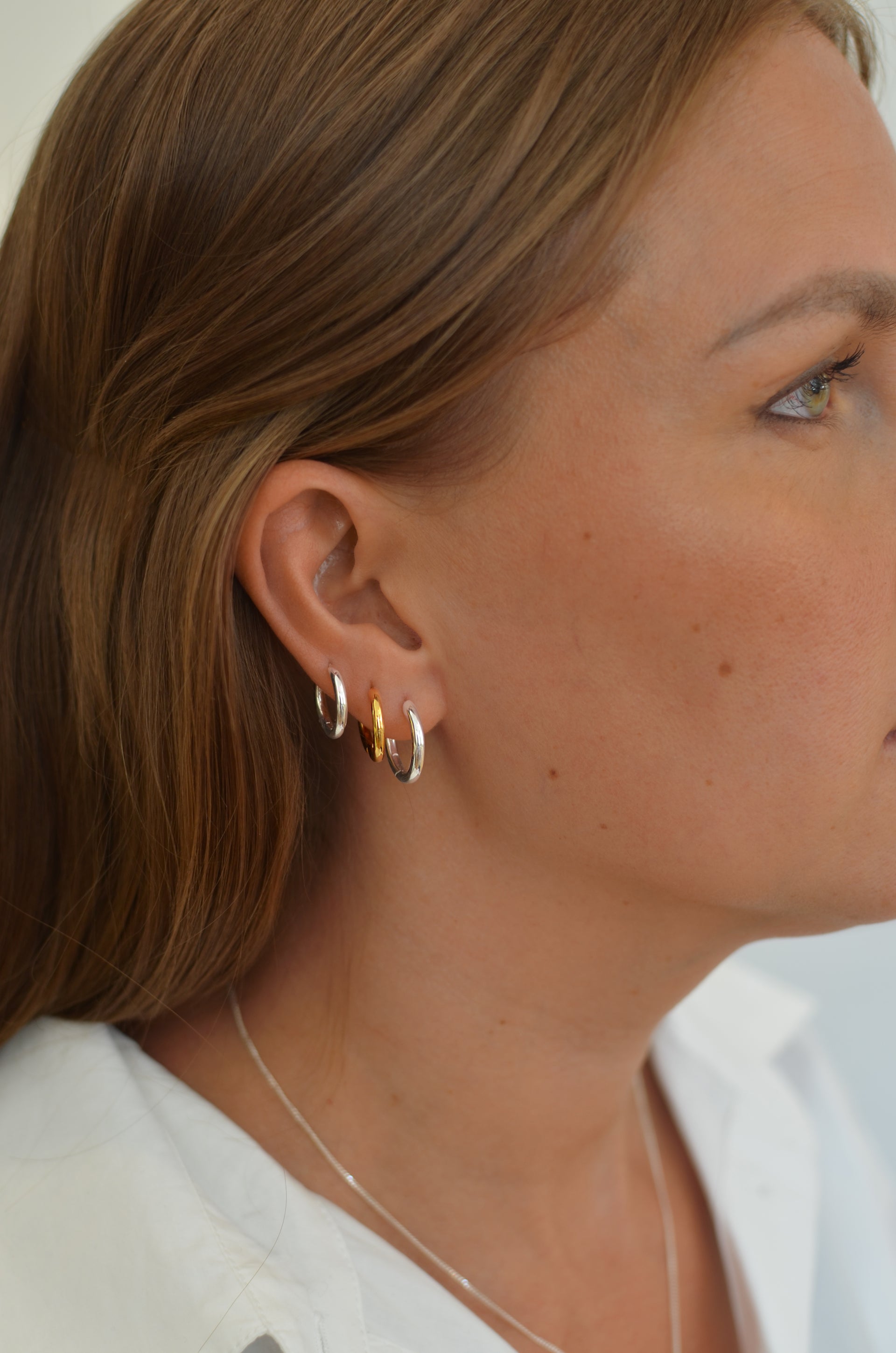 A large silver hoop and two medium hoops, one in silver and one in gold