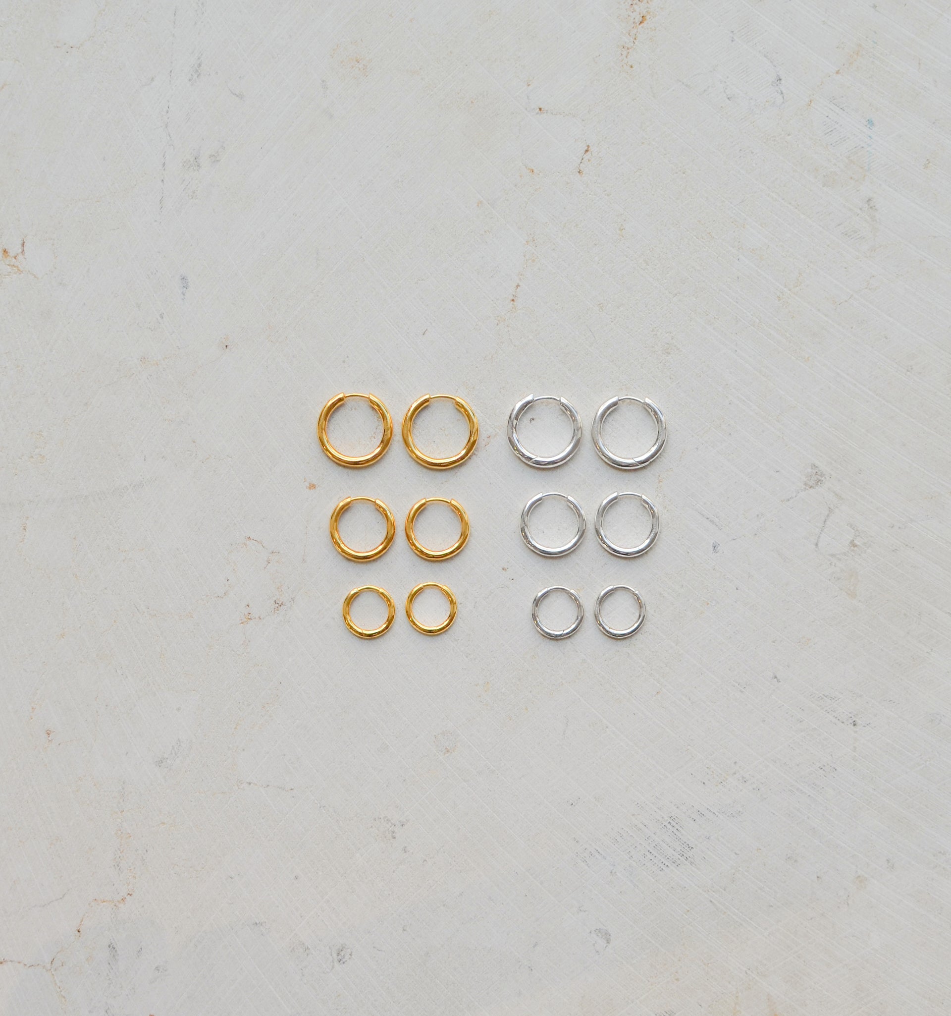 Gold hoops in various sizes next to silver hoops in various sizes