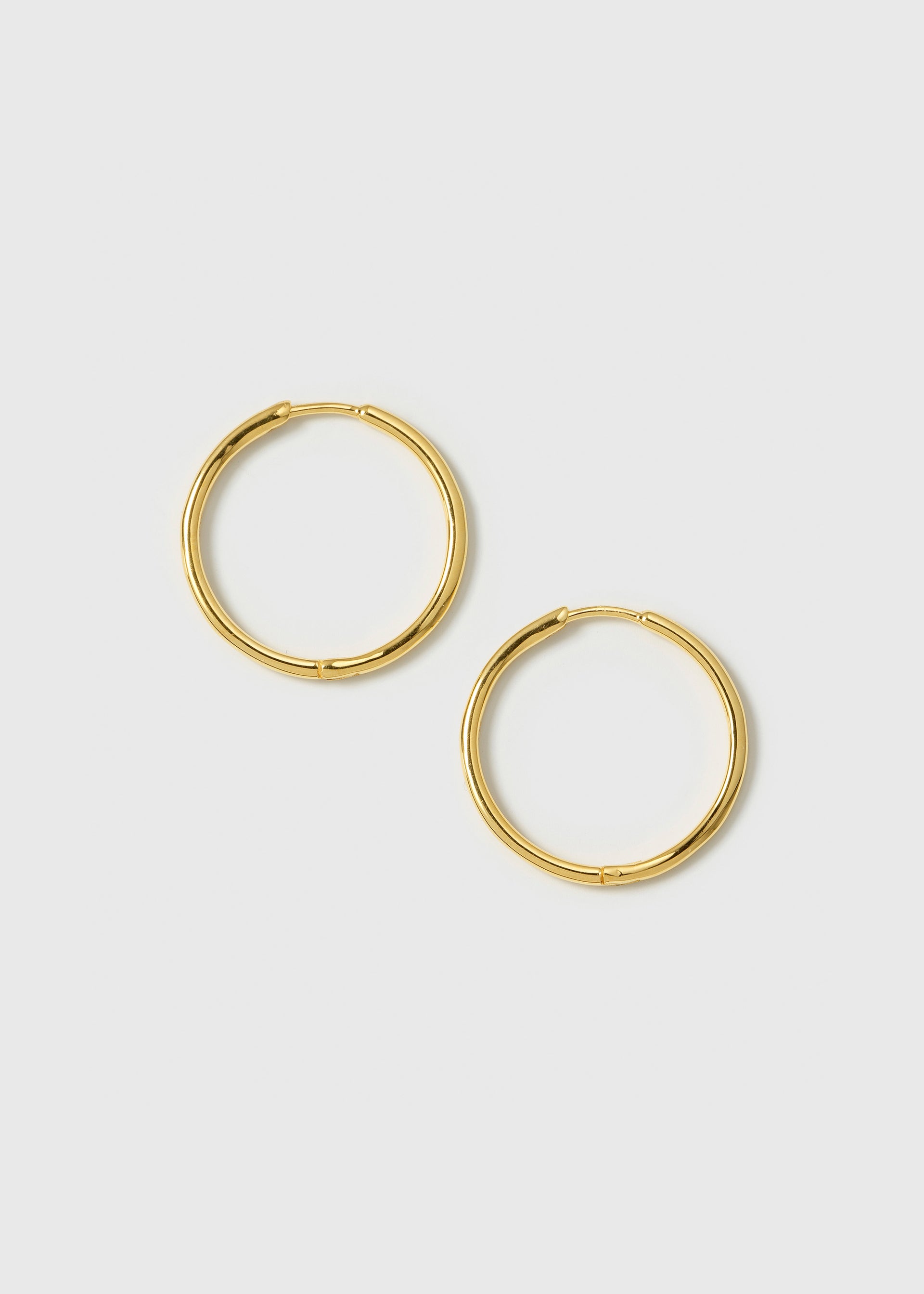 A product shot of the Beloved Medium Hoops in gold, laid out flat to showcase their classic, simple design.