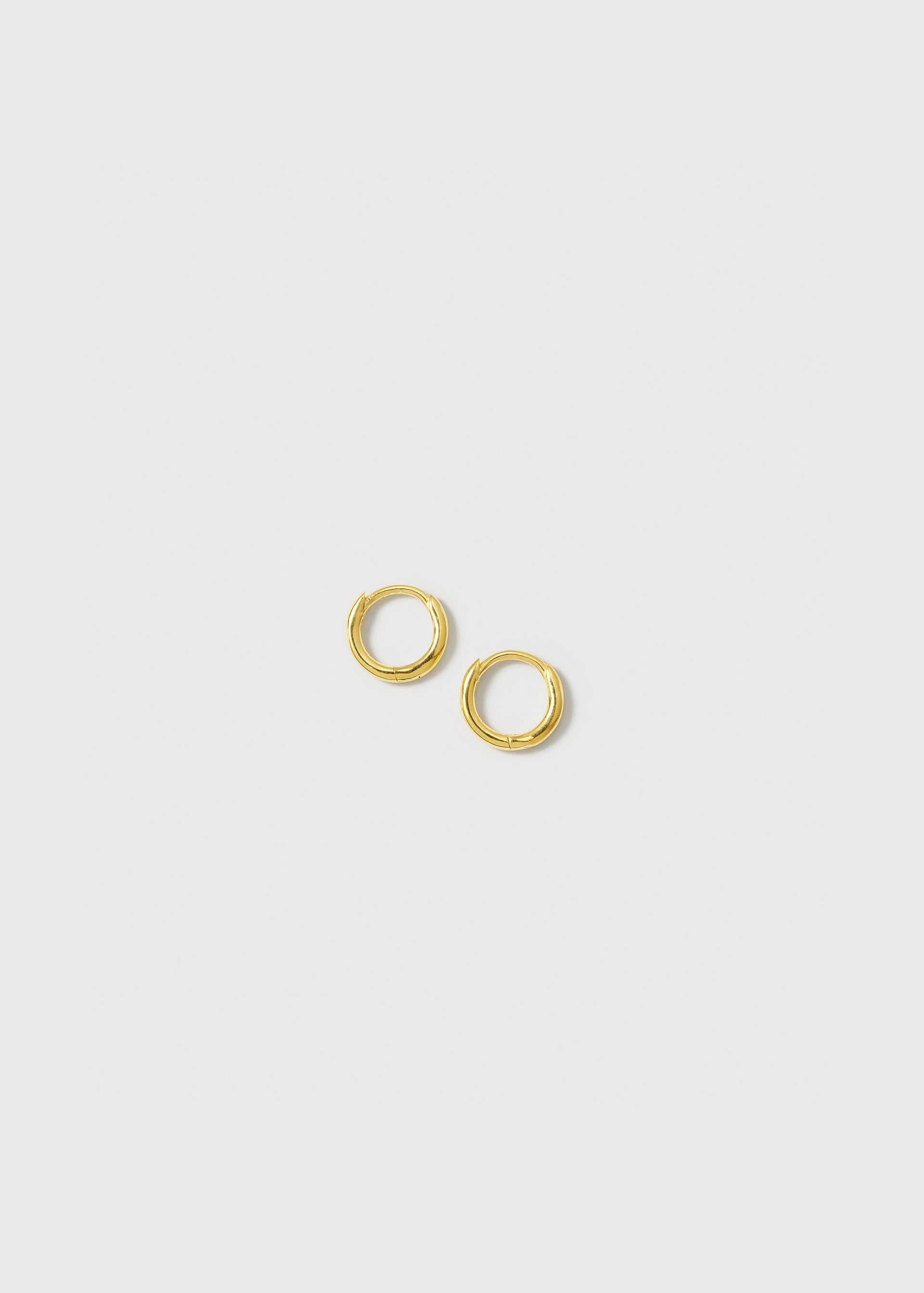 A product shot of the Beloved Mini Hoops in gold, a pair of small and classic hoop earrings with a smooth finish.