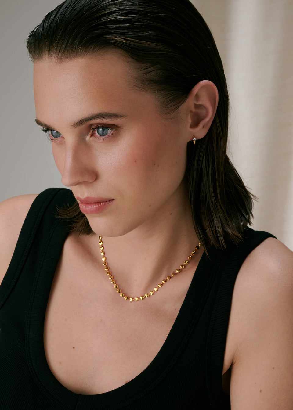 Gold hoop earrings with crystals and a gold linked-heart necklace.