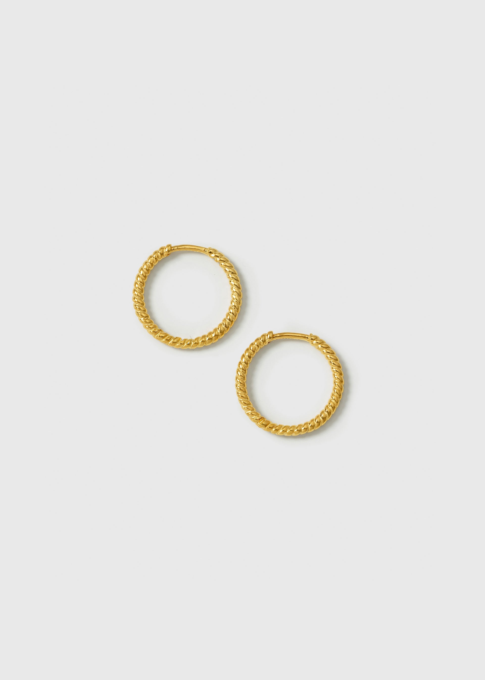 A product shot of the Beloved Twisted Medium Hoops in gold, laid out to showcase their unique twisted design.