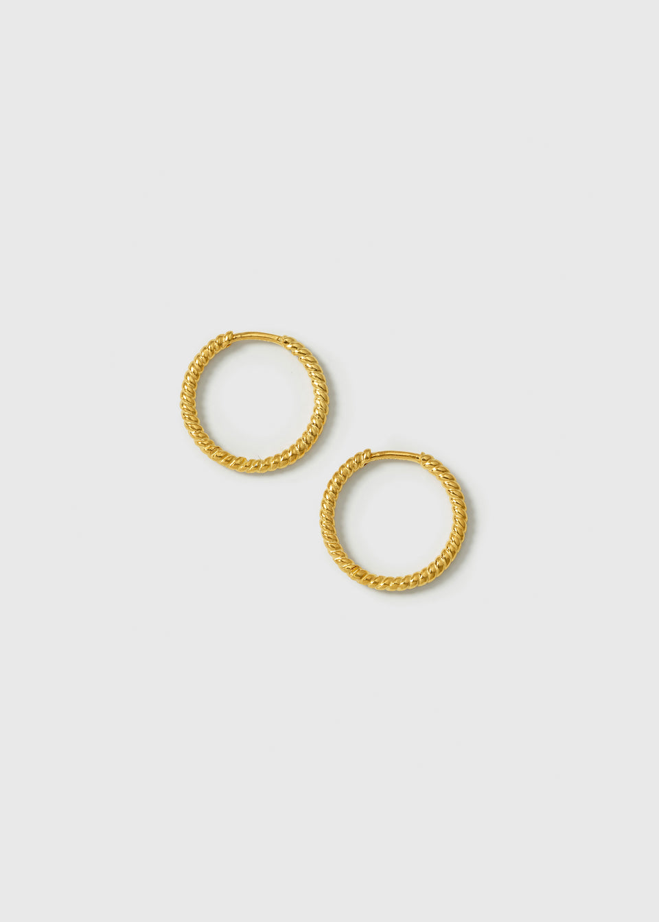 A product shot of the Beloved Twisted Medium Hoops in gold, laid out to showcase their unique twisted design.