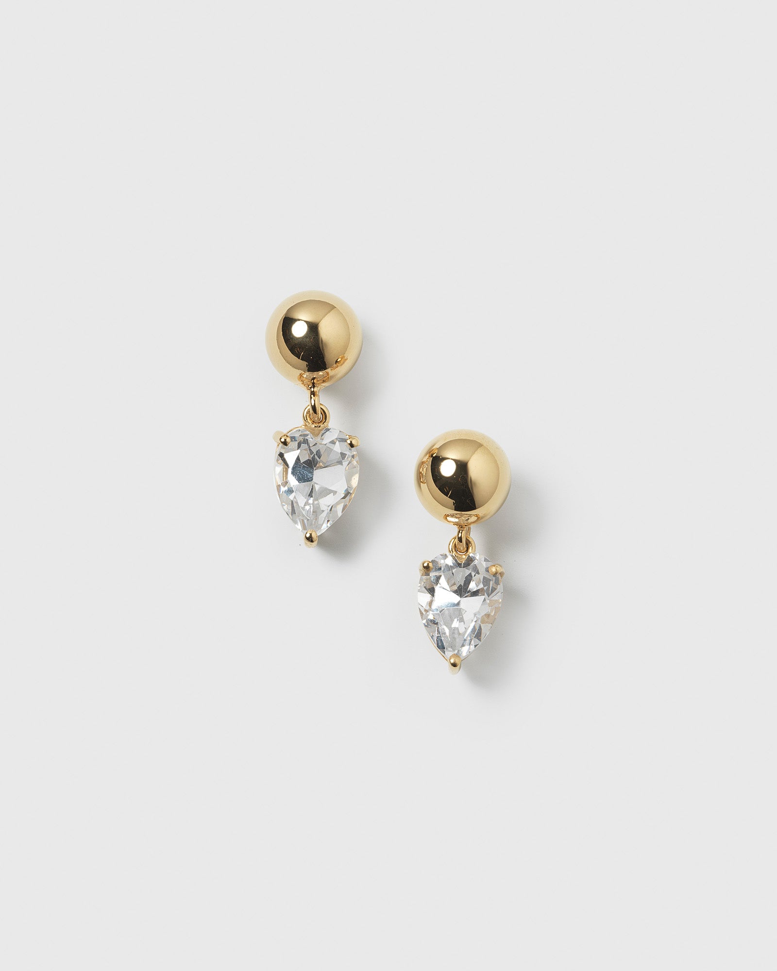 A product shot of the Katie Earrings in gold, featuring a round gold stud and a dangling drop-shaped cubic zirconia.