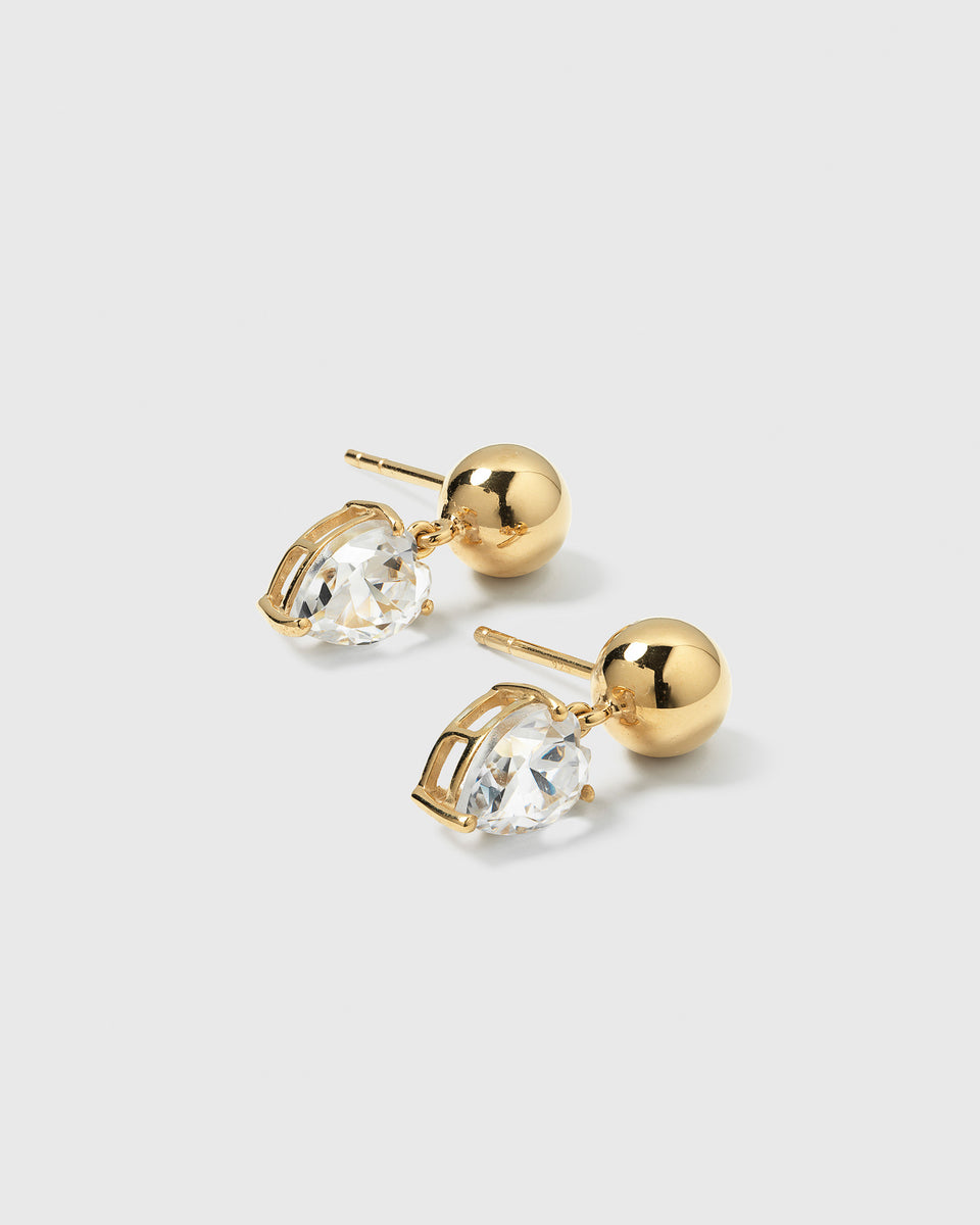A product shot of the Katie Earrings in gold, featuring a gold sphere stud with a dangling drop-shaped cubic zirconia.