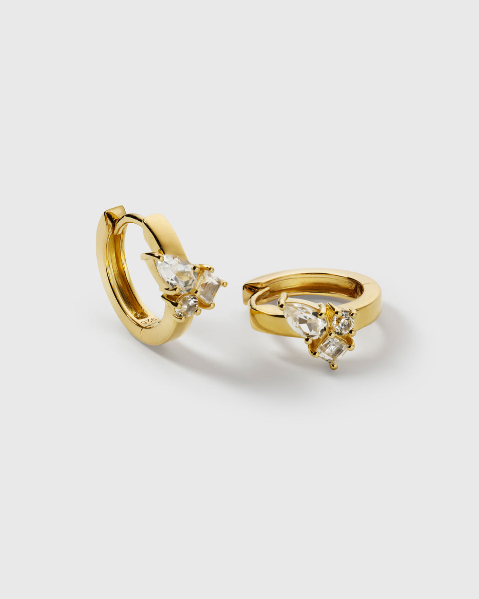 A product shot of the Pam Hoops in gold, showing the pair of earrings adorned with a cluster of brilliant white topazes.