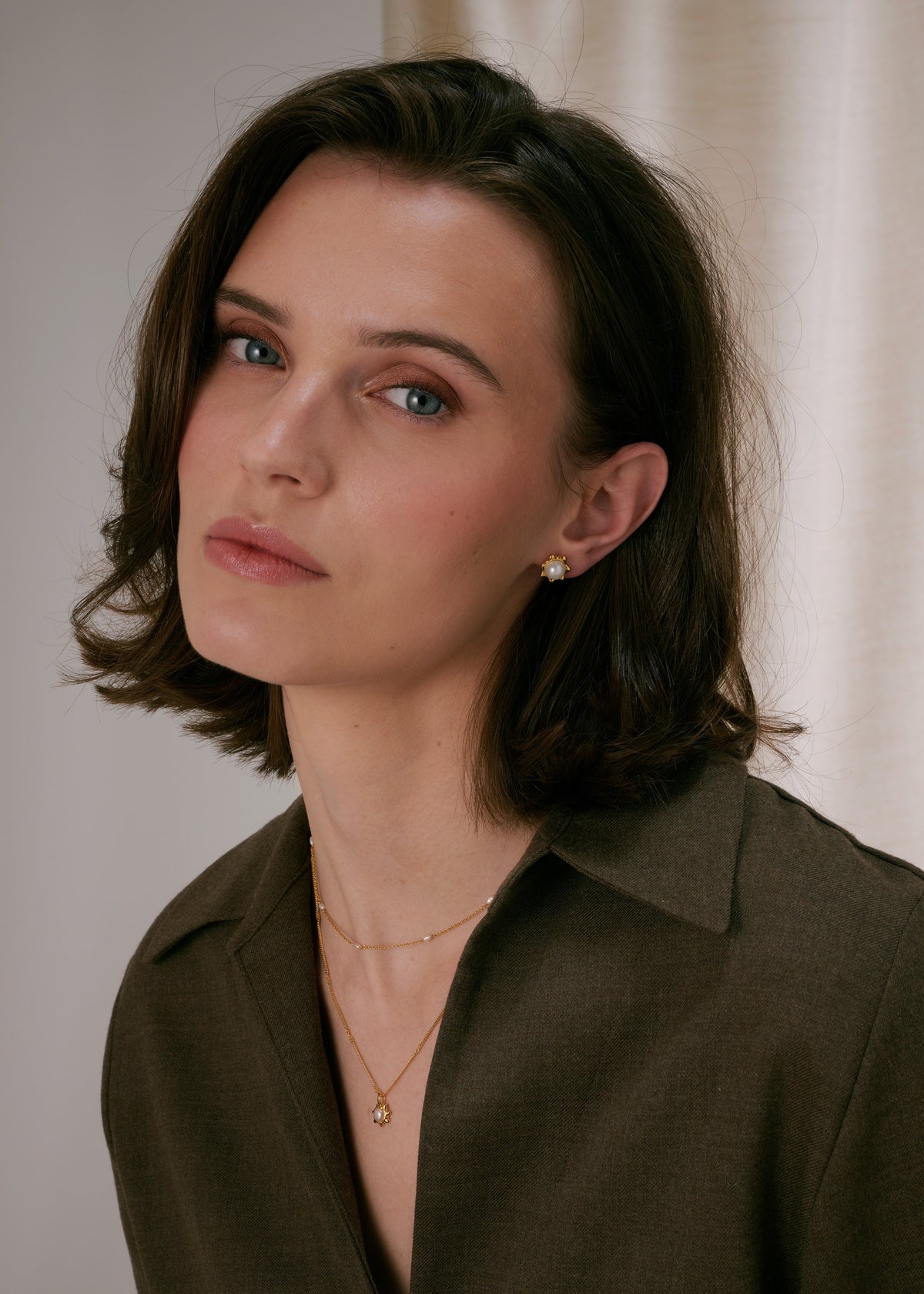 Gold stud earrings with a central freshwater pearl in a floral design, paired with a layered gold necklace‚Äîone chain with a matching freshwater pearl pendant and a shorter delicate chain with freshwater pearls.