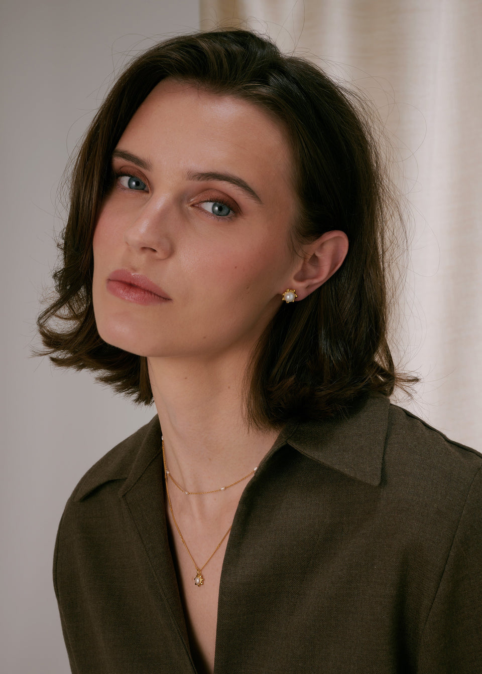 Gold stud earrings with a central freshwater pearl in a floral design, paired with a layered gold necklace‚Äîone chain with a matching freshwater pearl pendant and a shorter delicate chain with freshwater pearls.