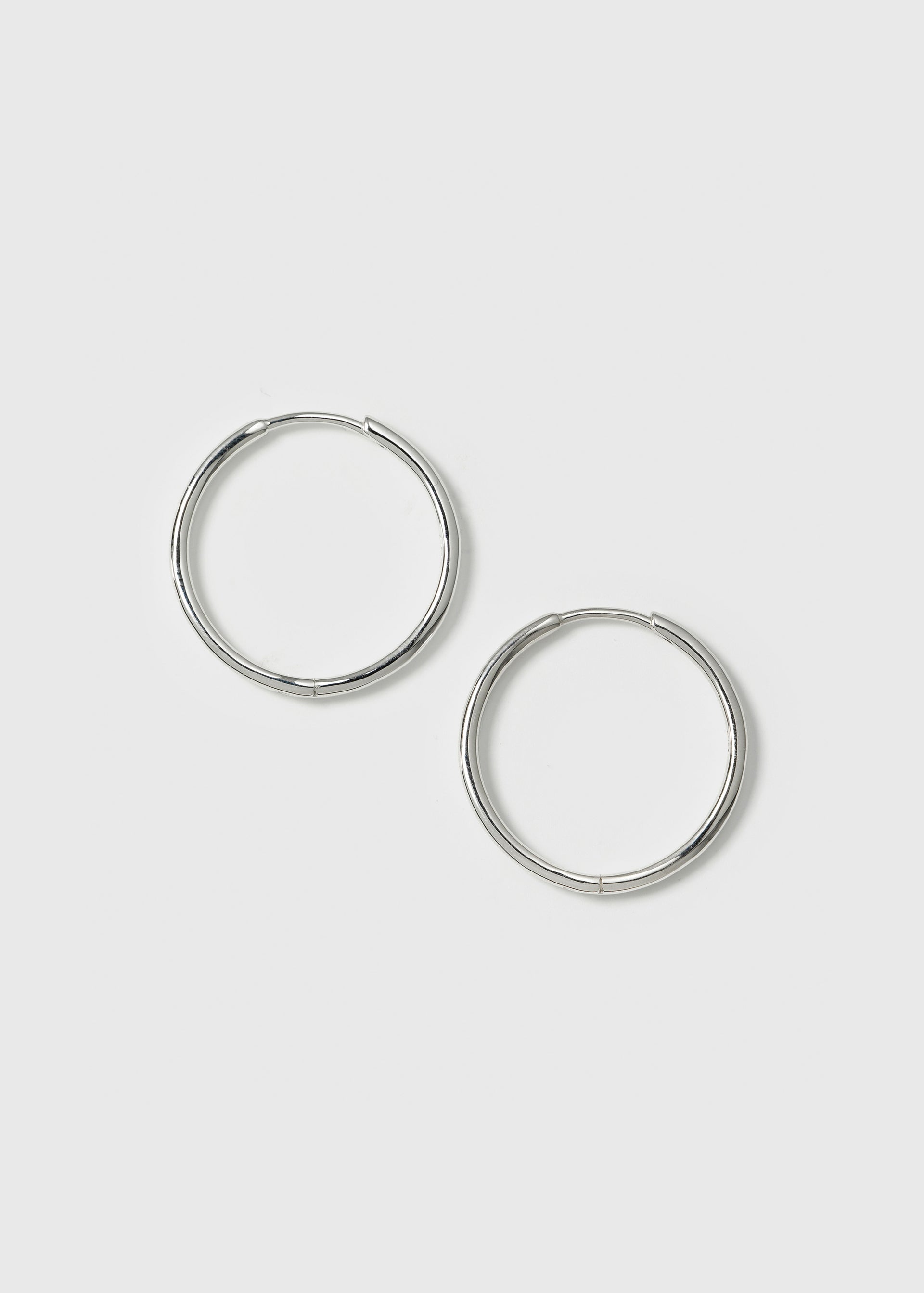 A product shot of the Beloved Medium Hoops Silver, a pair of classic and simple hoop earrings.