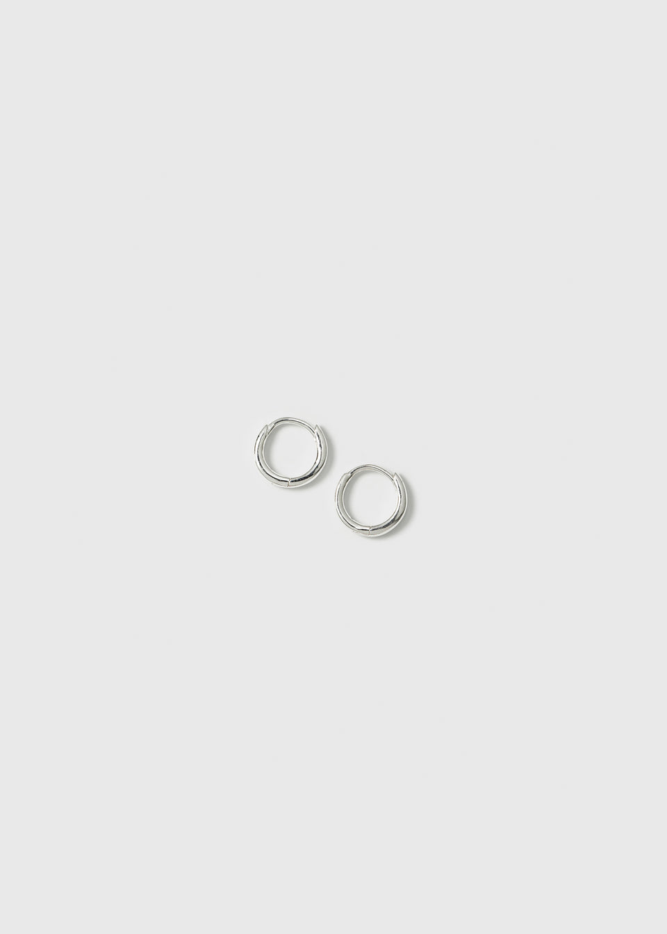 A product shot of the Beloved Mini Hoops in silver, a pair of small and classic plain hoop earrings.