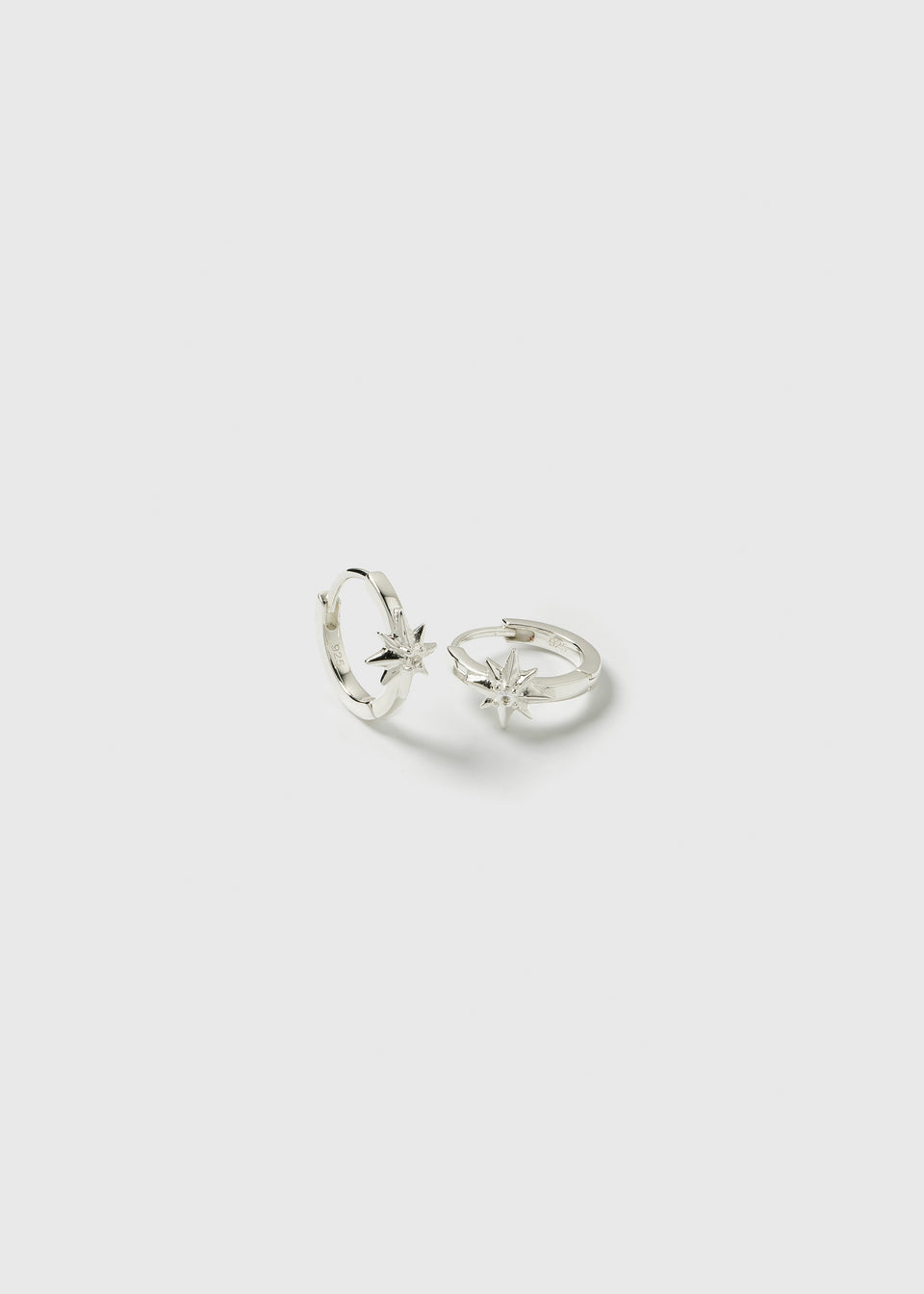 A product shot of the North Star Hoops in silver, showing the pair of small hoop earrings, each adorned with a North Star charm set with a single crystal.