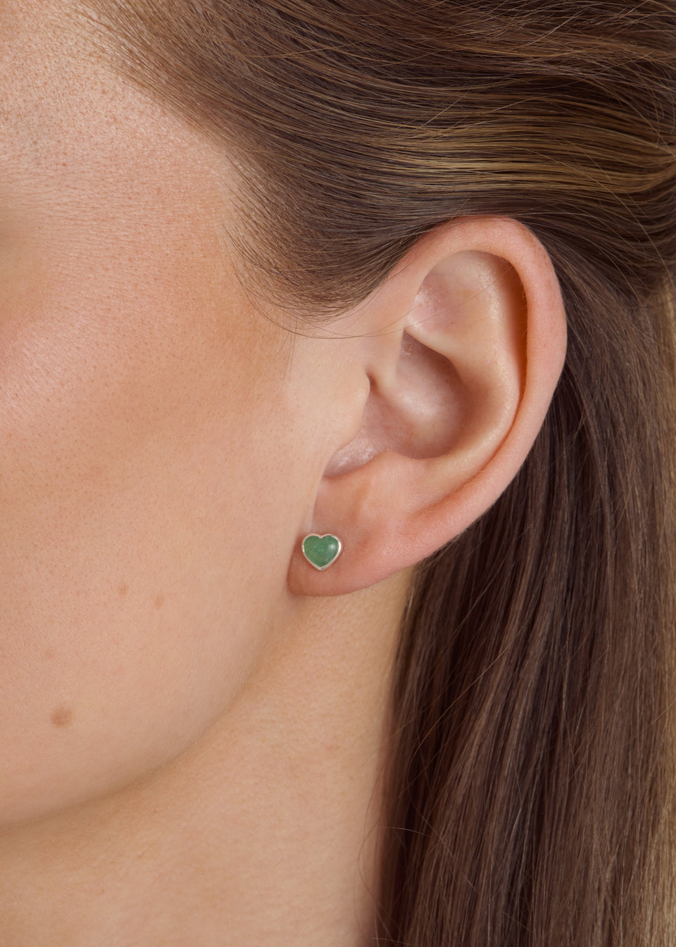 Close-up of a model wearing the silver La La Love stud earring with a heart-shaped green jade stone and silver frame.