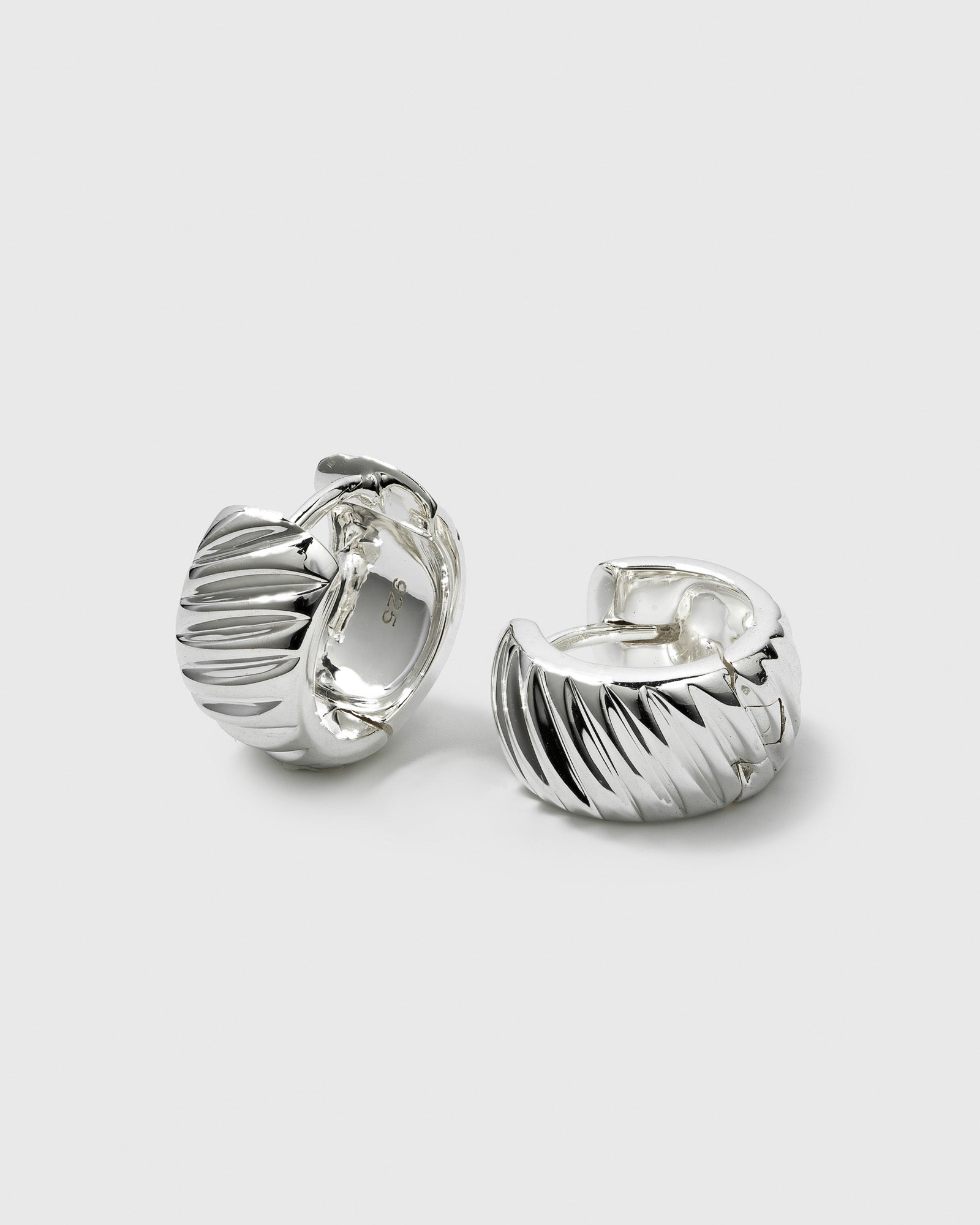 A close-up studio shot of the La La Love Plain Hoops in silver. The image displays the pair of chunky earrings, highlighting their ribbed, textured finish.