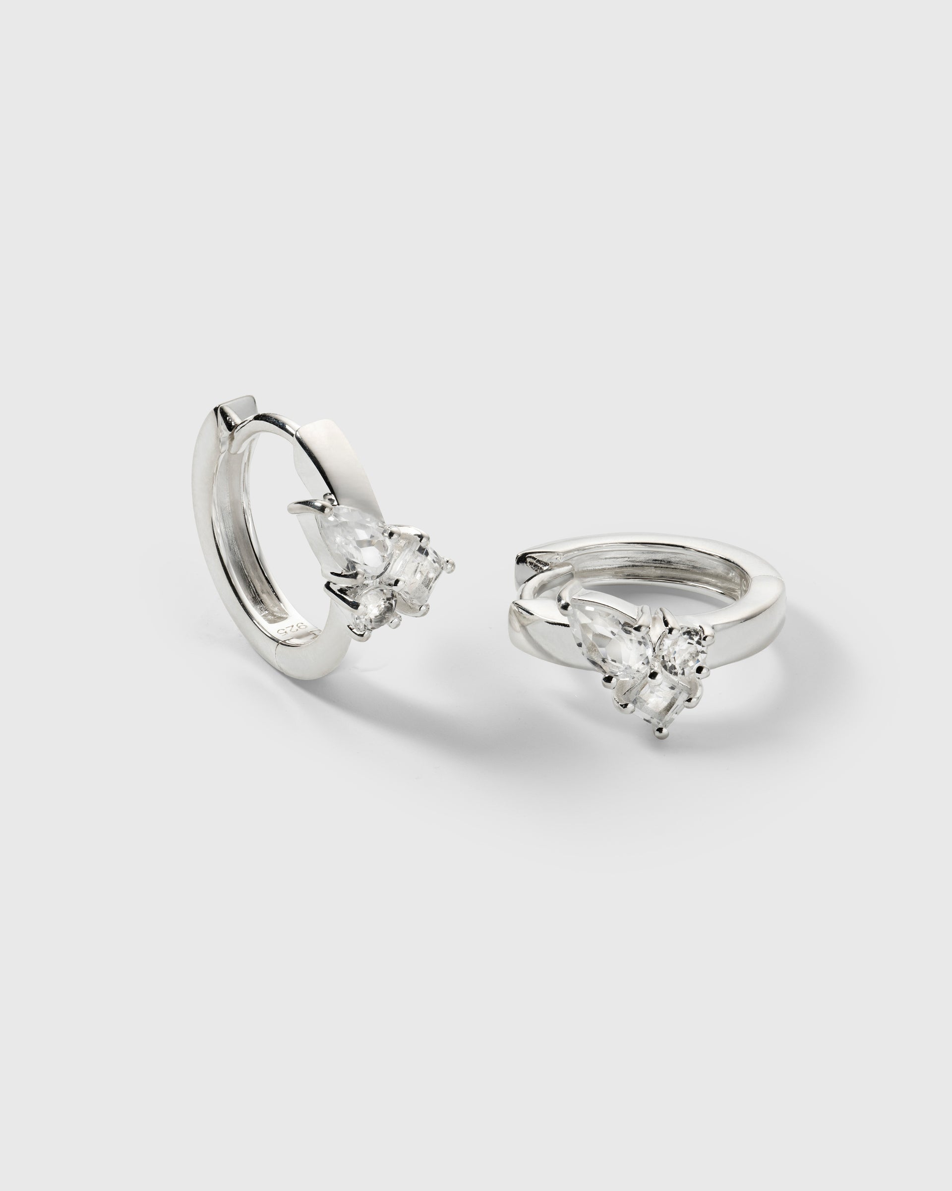 A product shot of the Pam Hoops in silver, showcasing the pair of recycled sterling silver earrings adorned with a cluster of brilliant white topazes.