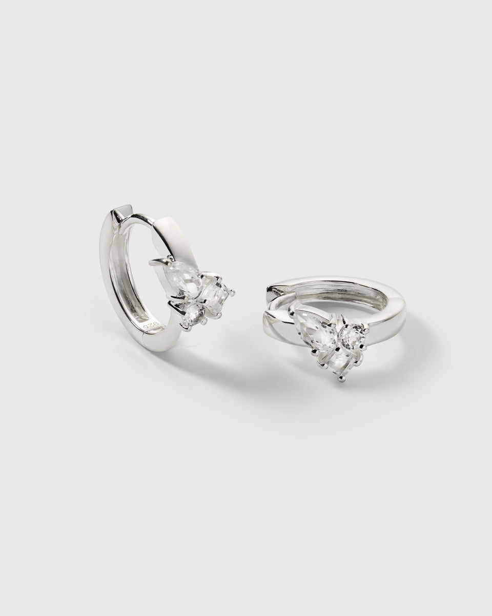 A product shot of the Pam Hoops in silver, showcasing the pair of recycled sterling silver earrings adorned with a cluster of brilliant white topazes.