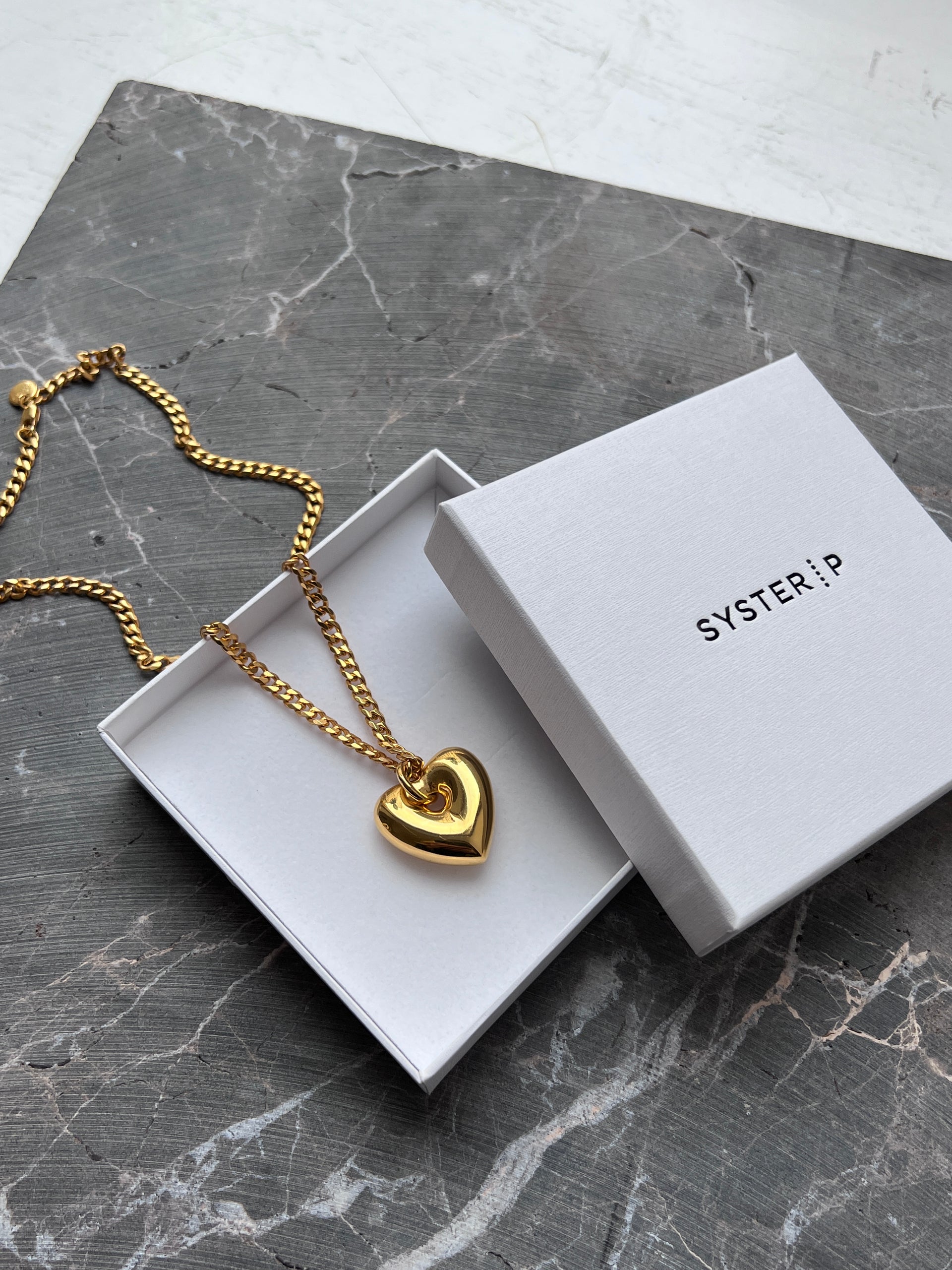 A gold necklace with a fat heart