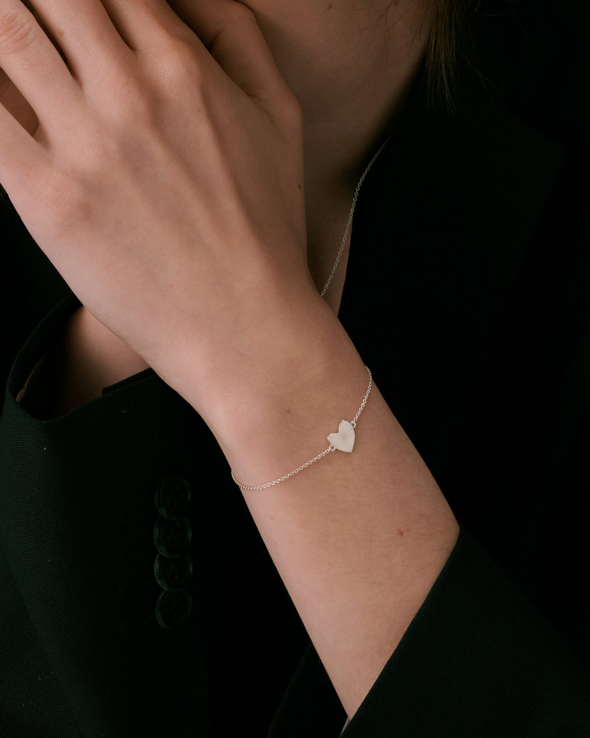 A delicate silver chain bracelet with a hammered heart charm, paired with a fine silver chain necklace.