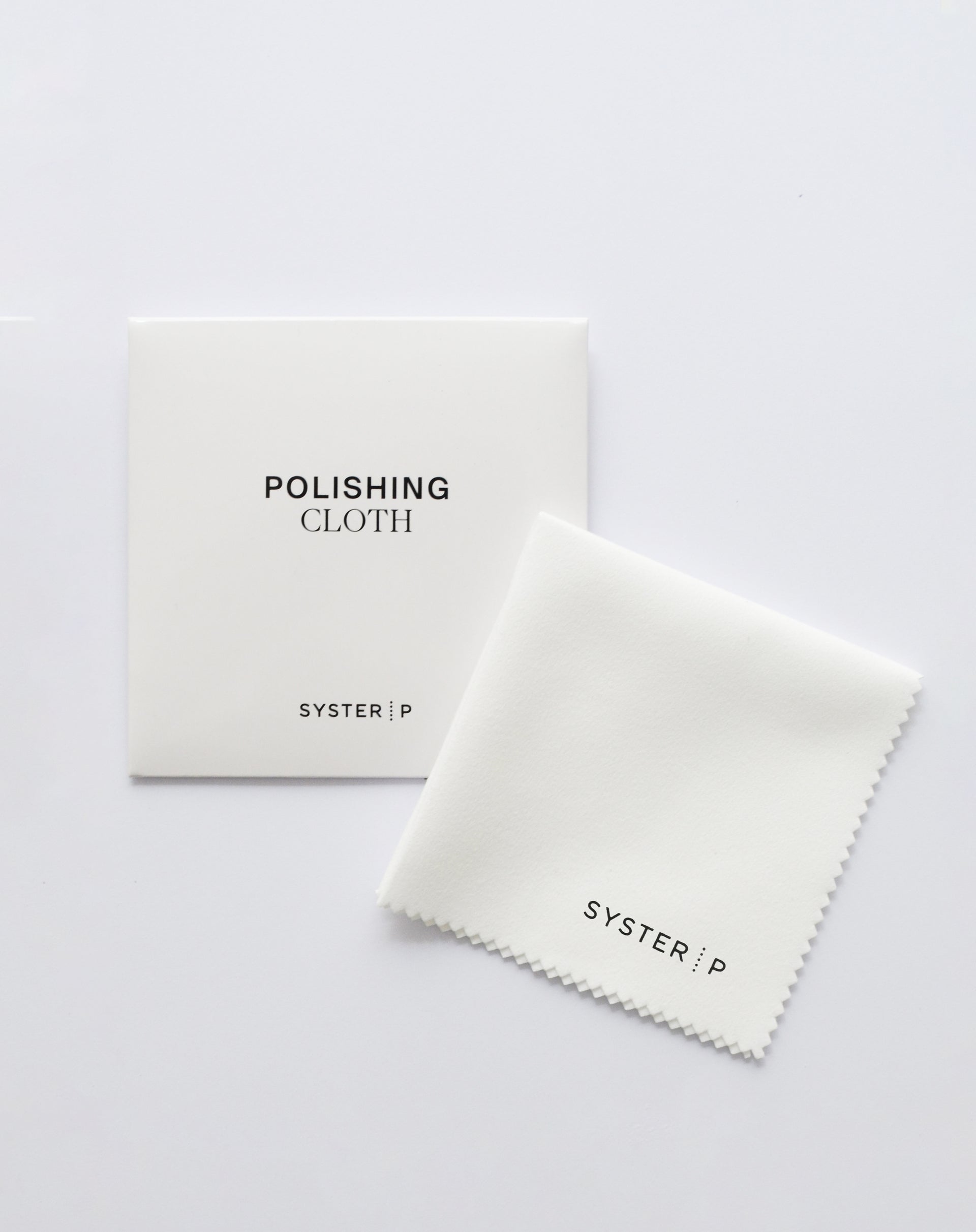 A product shot of the white Syster P Polishing Cloth, displayed unfolded next to its matching white packaging sleeve.